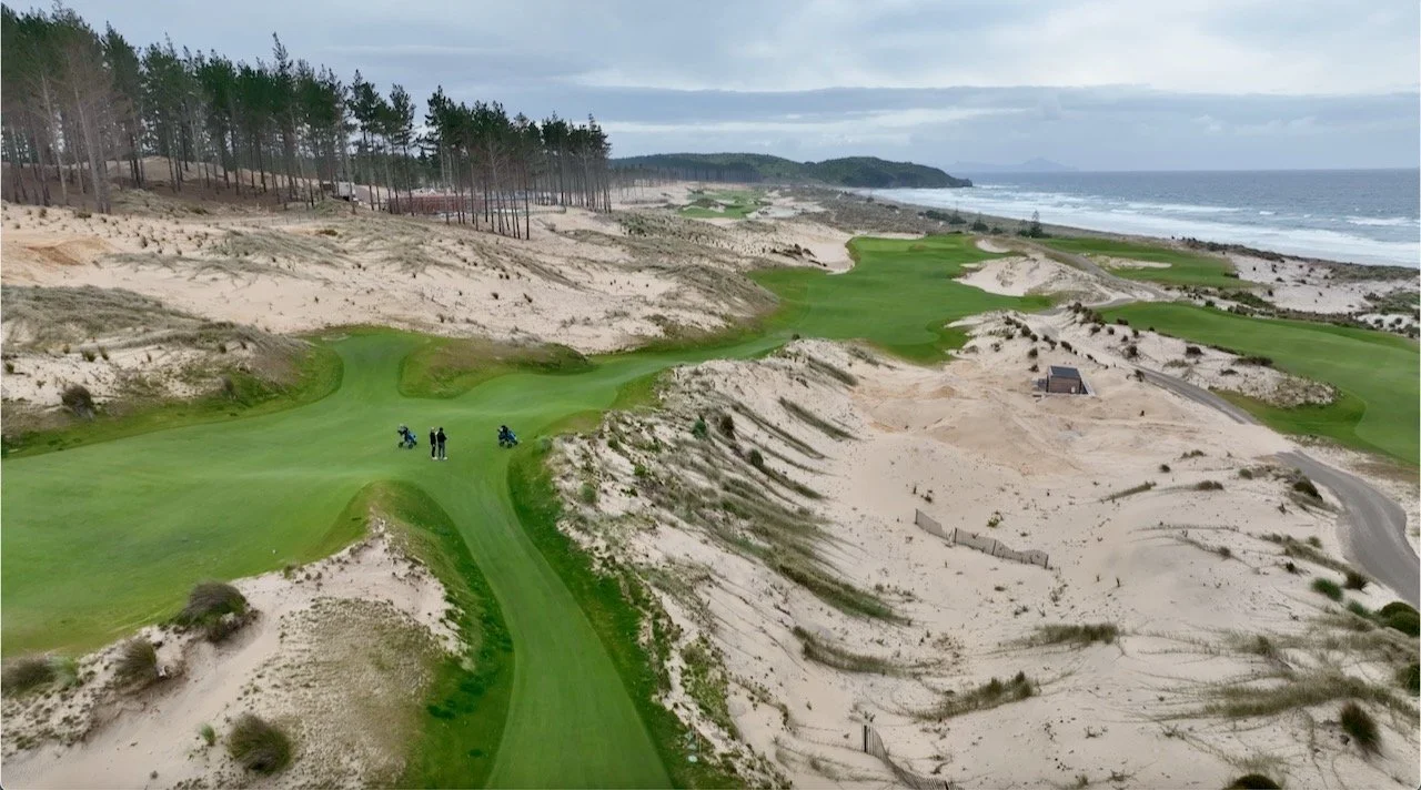 aerial view of a coastal golf course with sand dunes and ocean