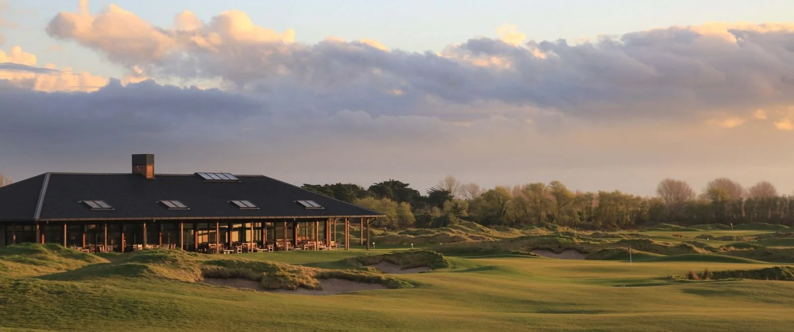 Golf club building with lush green landscape and cloudy sky