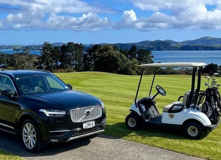 Black tour vehicle and golf cart with equipment parked on a scenic coastal New Zealand golf course fairway