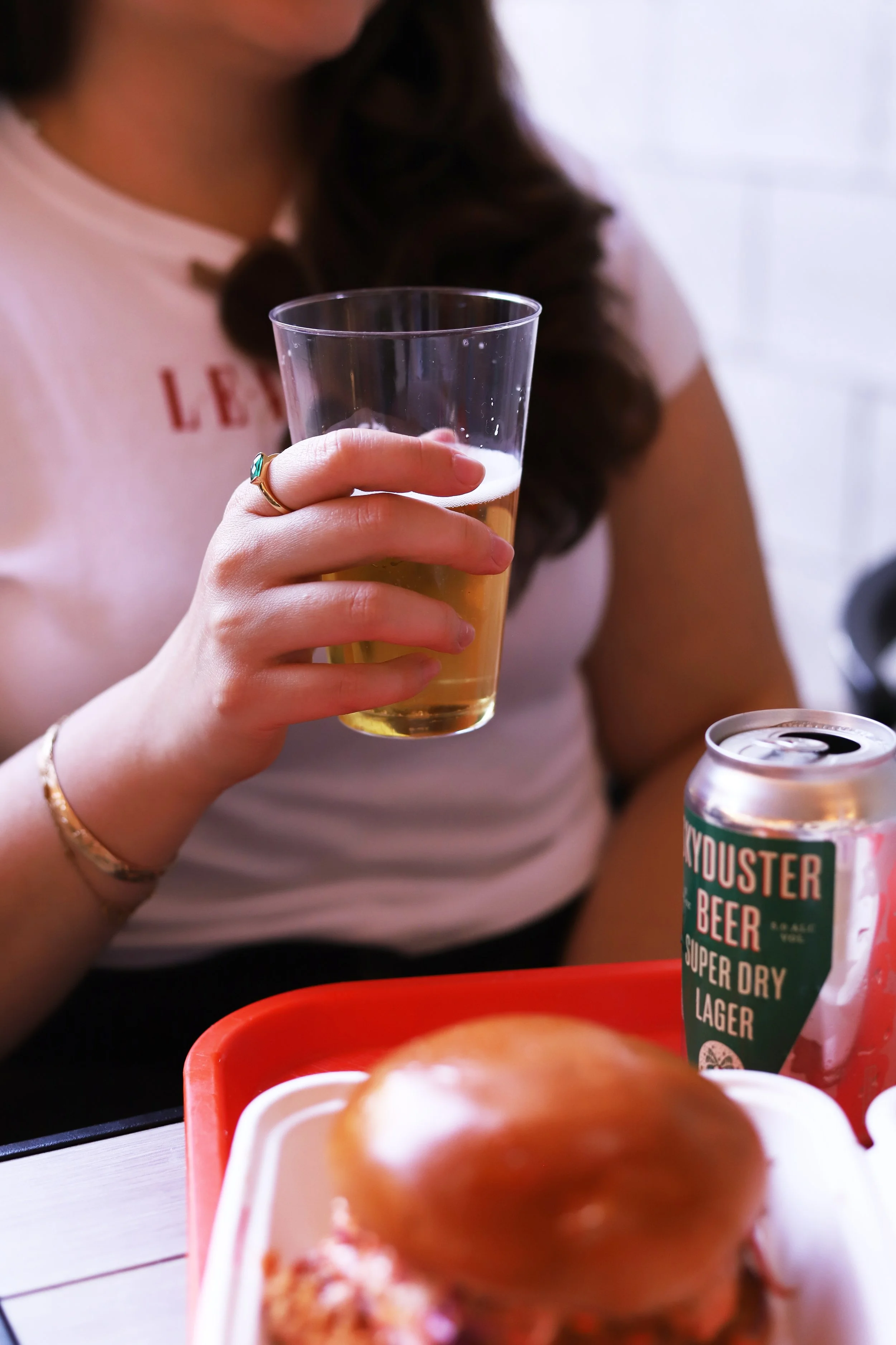 Holding a Skyduster beer with a fried chicken sandwich at the best chicken restaurant in Los Angeles