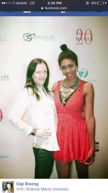 Two women standing together at an event, smiling in front of a backdrop with logos and text.