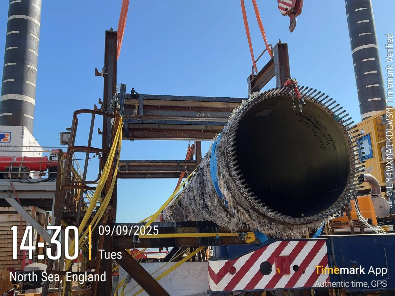 Large pipe being lifted by construction equipment on a platform, with scaffolding and lifting straps, against a clear blue sky in North Sea, England, on September 9, 2025.