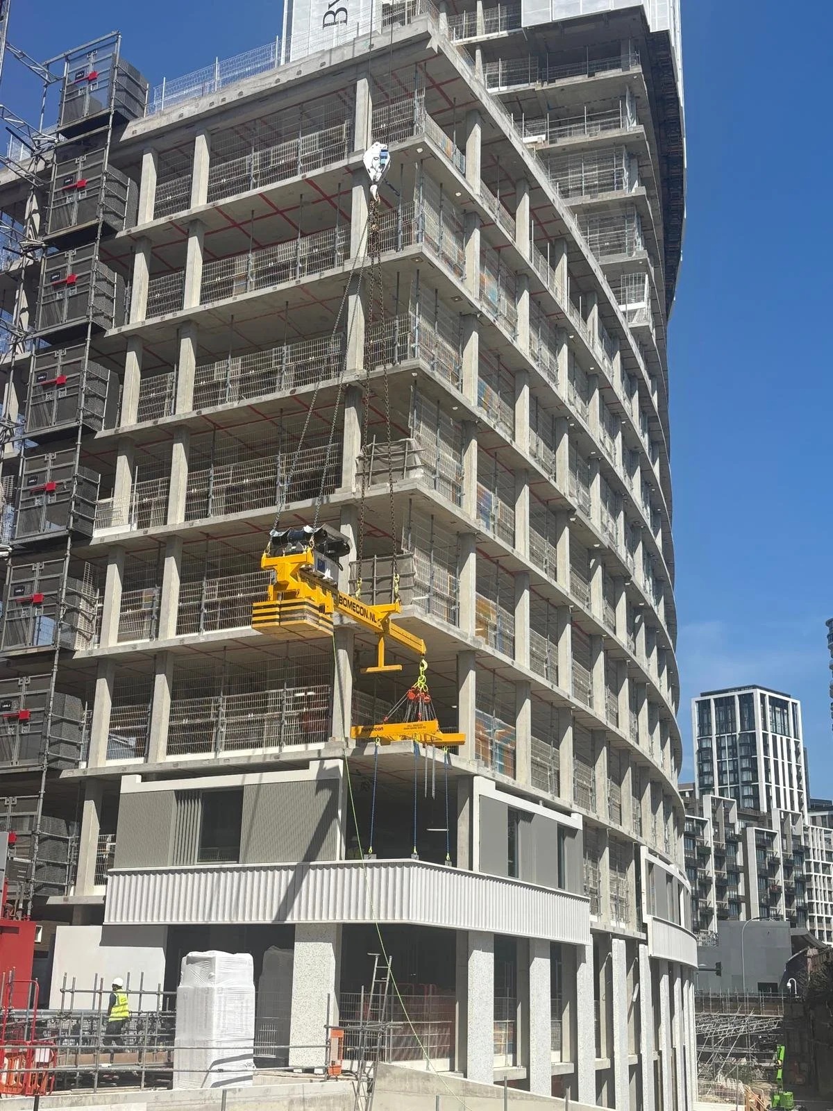 Construction site of a modern multi-story building with cranes and scaffolding, and workers.
