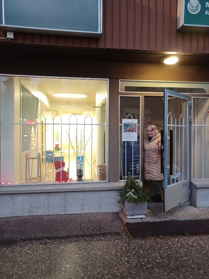 Nastola-seuran toimisto ulkoapäin kuvattuna. Valkoinen, matala rakennus, jonka vieressä kasvaa mäntyjä. Foto: Erkki Hämäläinen