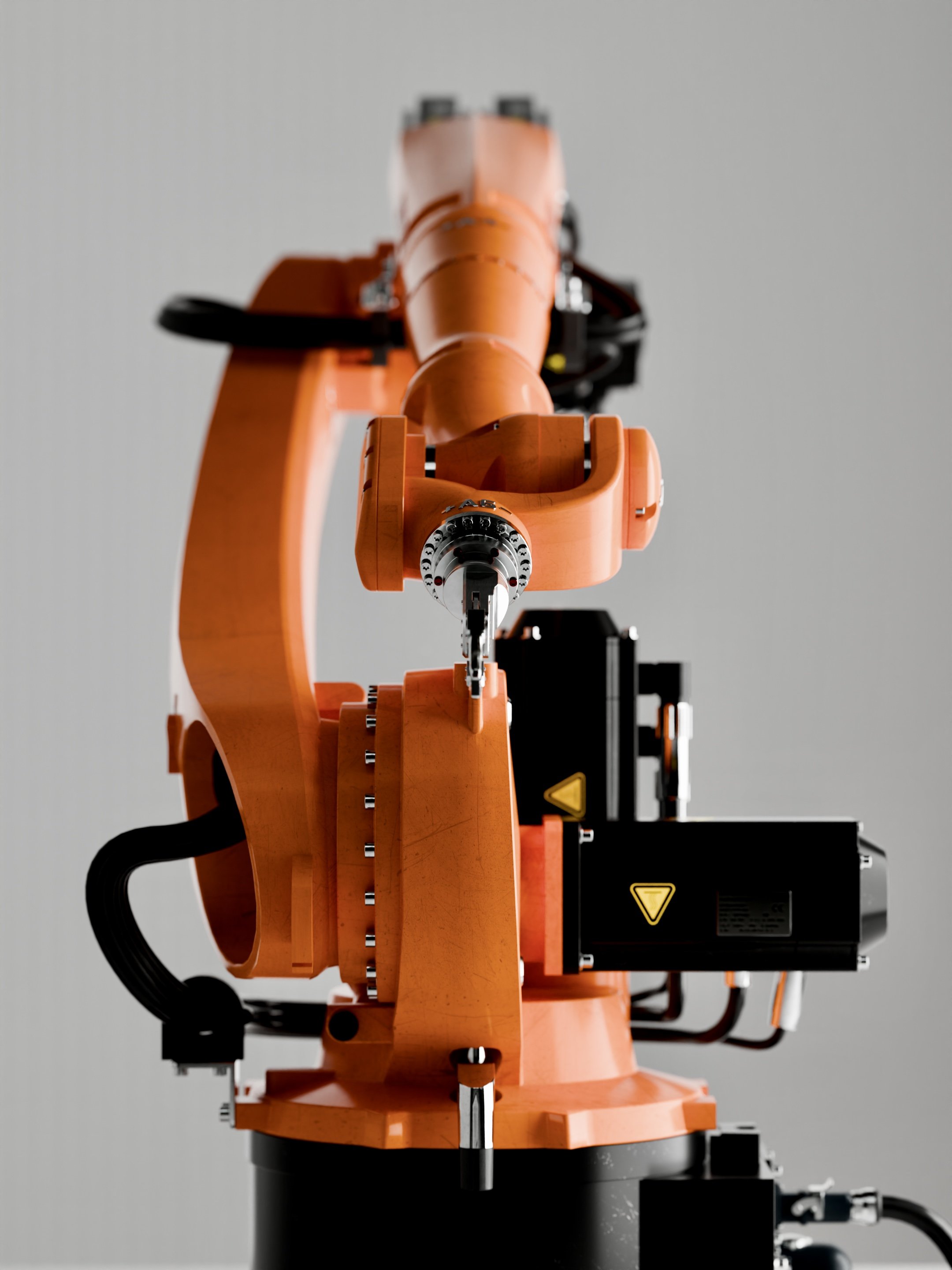 A large robotic arm, orange in color, with mechanical joints and a black base, set against a plain gray background.