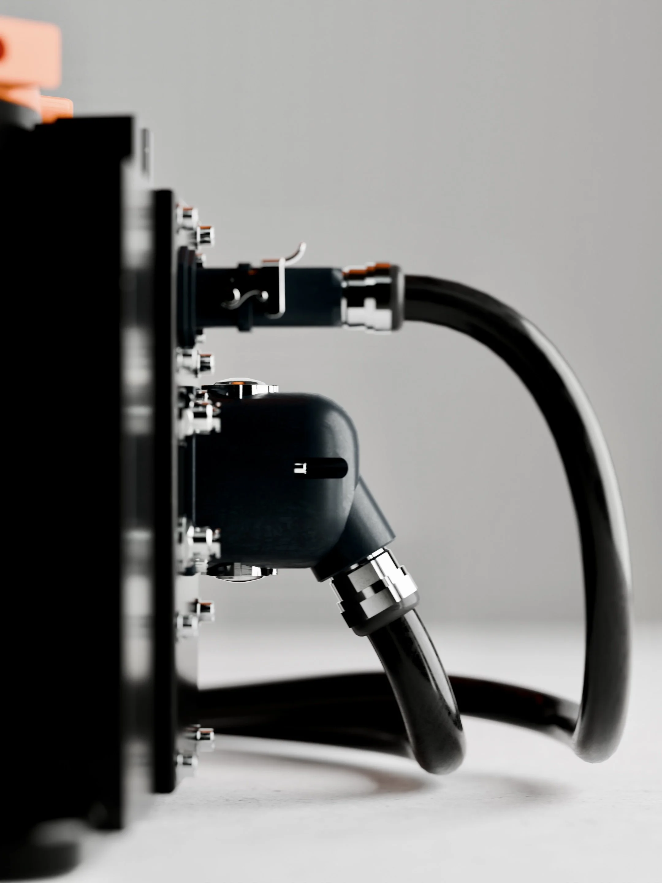 Close-up of a scientific instrument with metal tubing and connectors against a plain, light grey background.