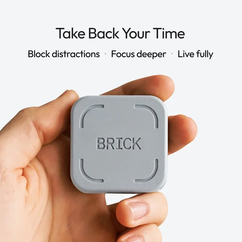 Person holding a grey square block with the word 'BRICK' engraved on it.