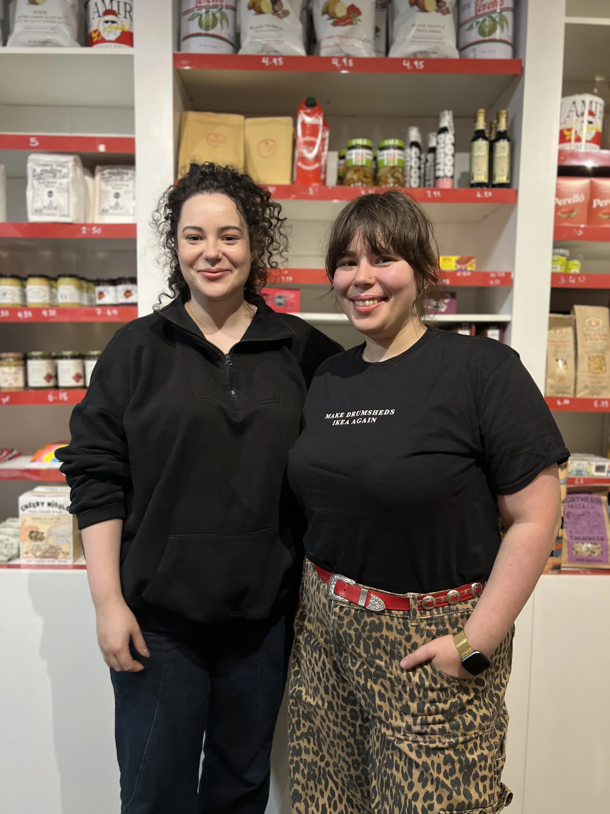 Two sisters stand in front of deli shelves