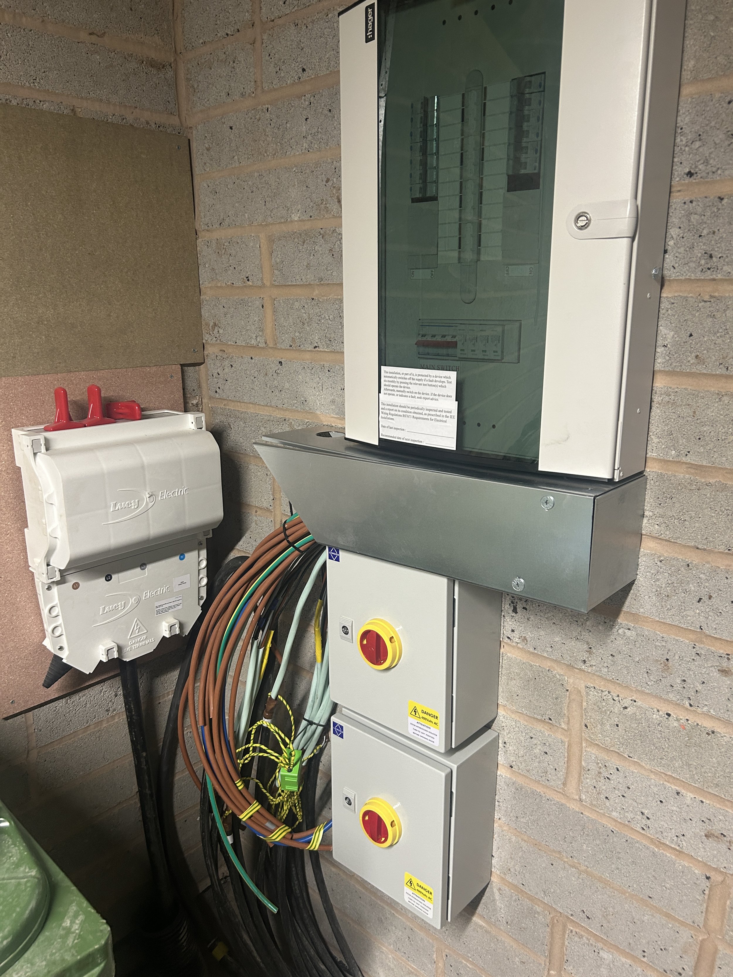 Electrical control panels and wiring mounted on a brick wall in an industrial or utility setting.