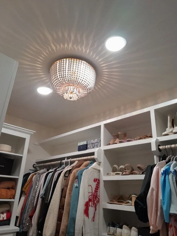 Walk-in closet with chandelier and clothing on racks