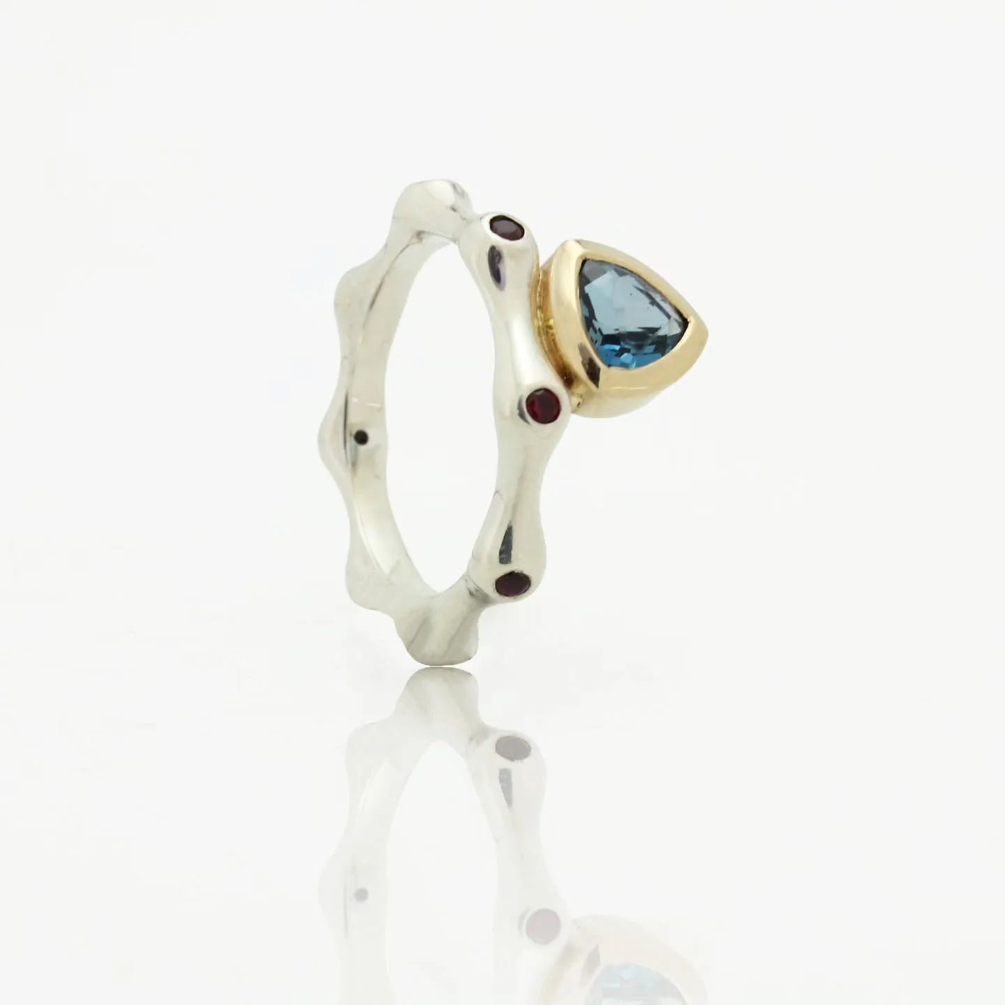 Bold. Organic. One of a kind. 💍✨
This ring carries the movement of water in its flowing silver band, a golden bezel holding a deep blue gem like sunlight over the sea, and garnets scattered like sparks of fire. Every detail is intentional — a