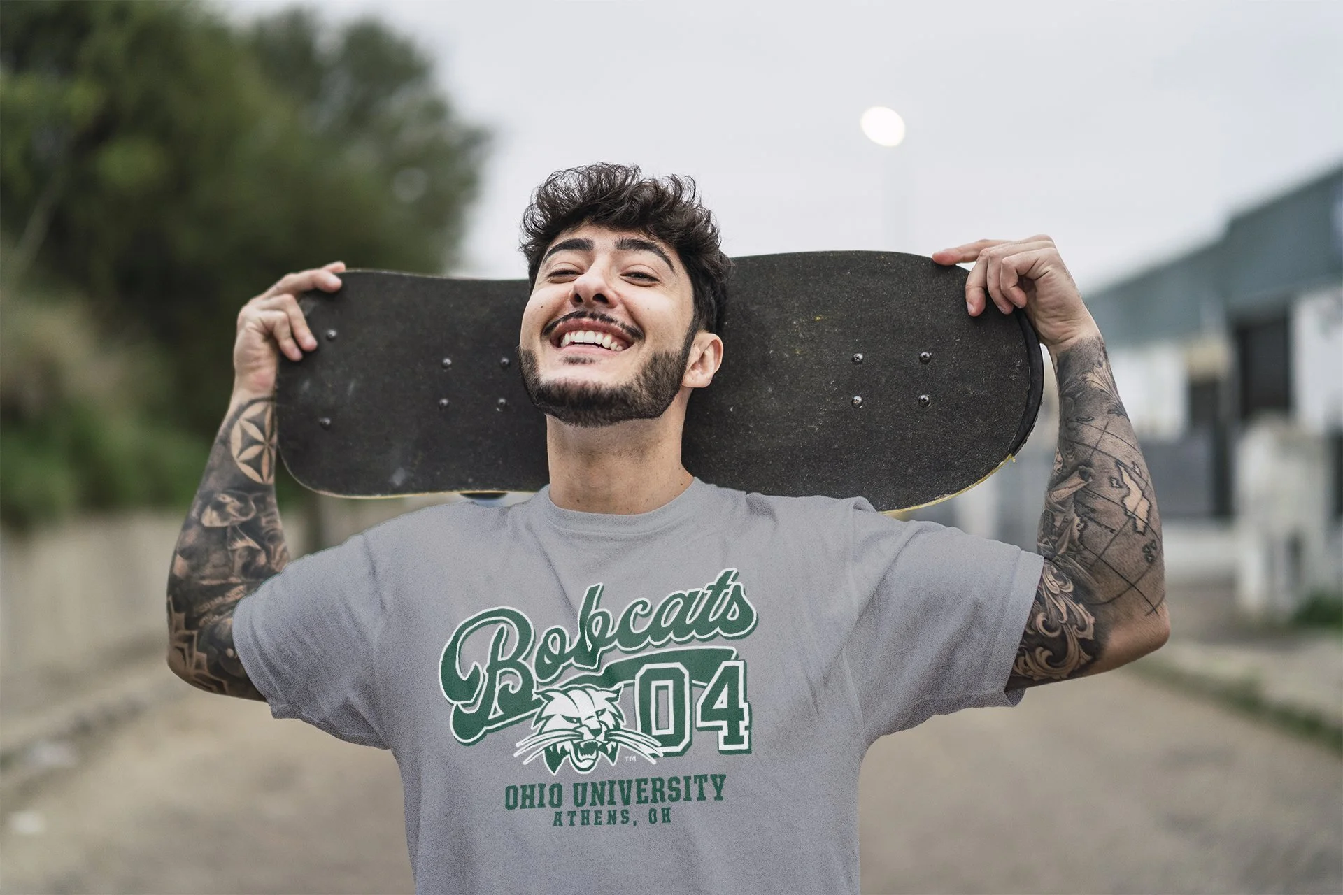 young-smiling-european-cool-male-holding-skate-blurred-setting-street.jpg