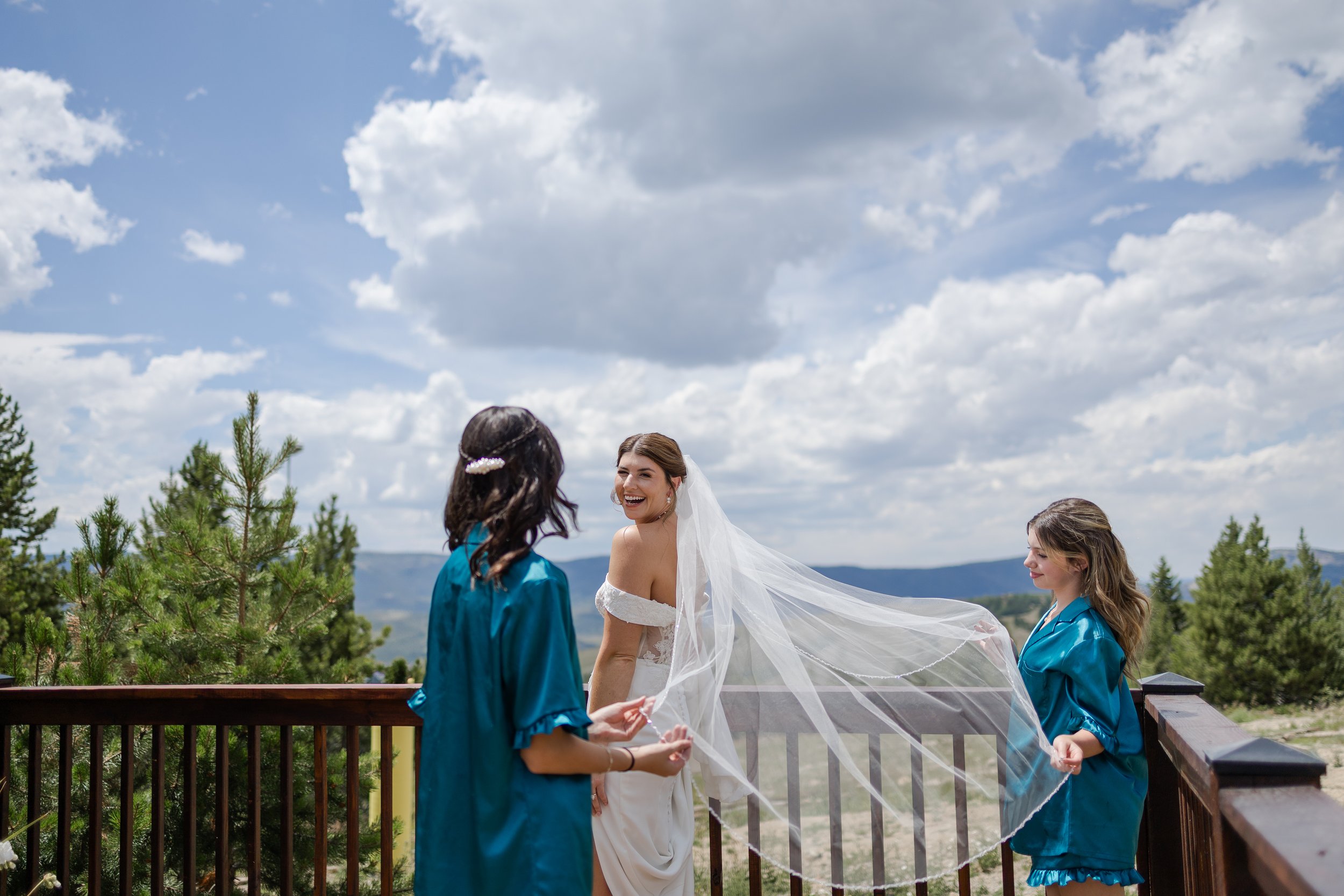 Bride posing with her daughters with her veil before her wedding ceremony at Granby Ranch. Photography by Trail Magic Elopements and Micro Weddings.