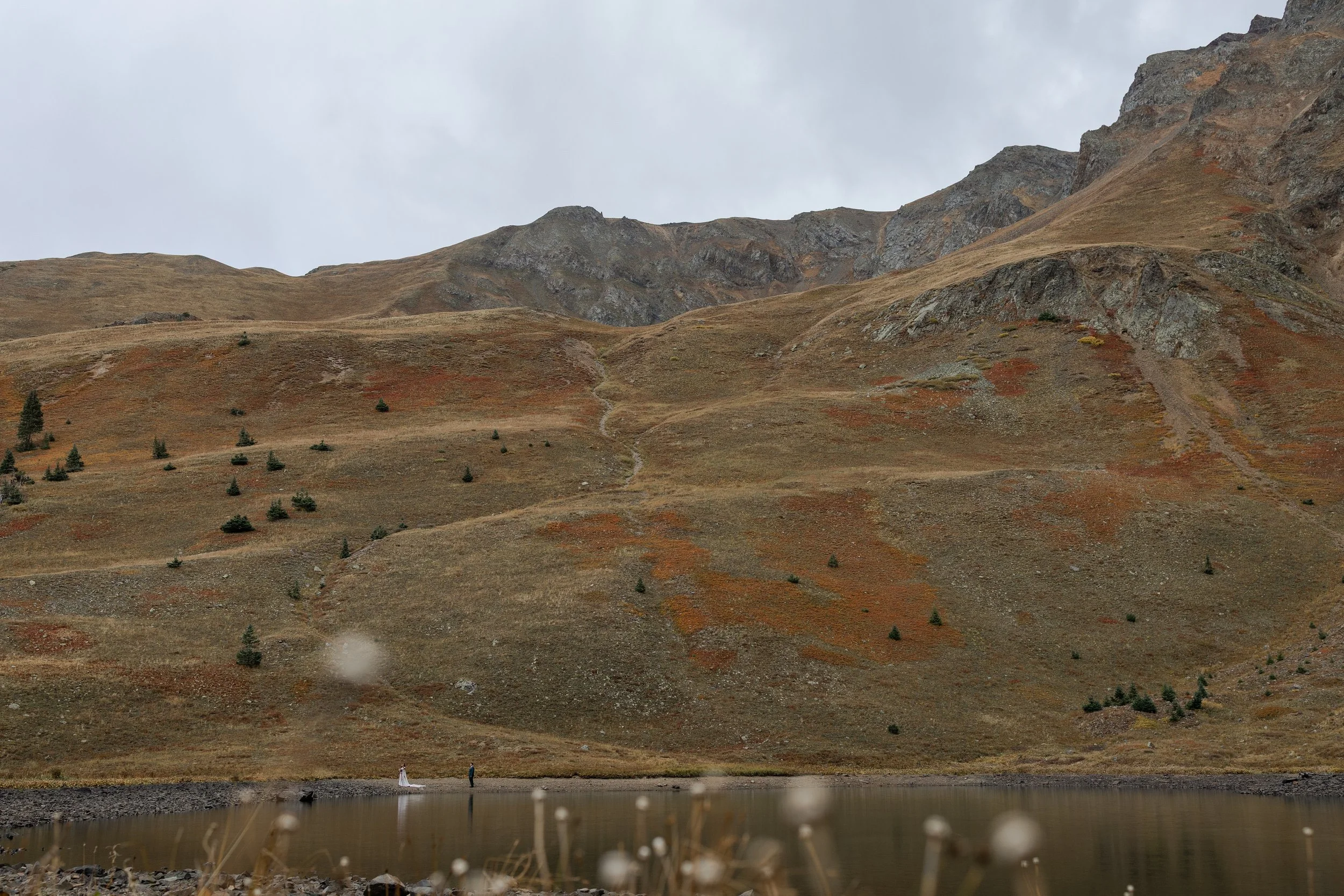 Couple walking along alpine like on their elopement day in the San Juan Mountains. Photography by Trail Magic Elopements and Micro Weddings.