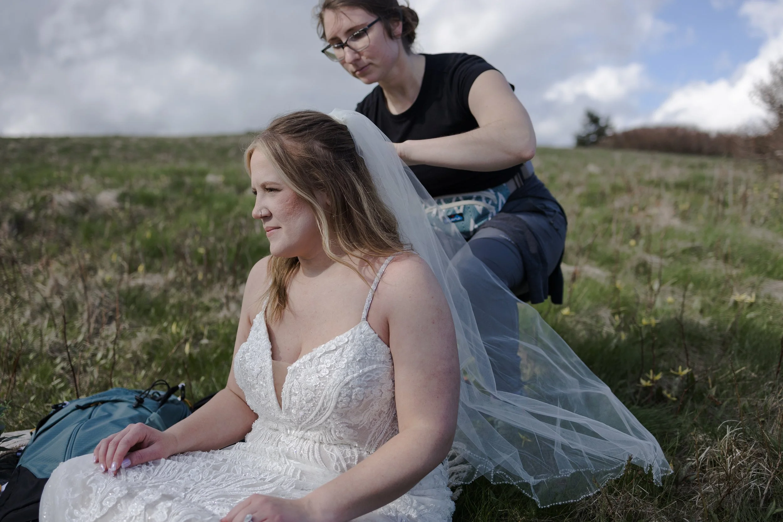 Elopement planner helping a bride put on her veil before her elopement ceremony on Roan Mountain, Tennessee. Photography by Trail Magic Elopements and Micro Weddings.