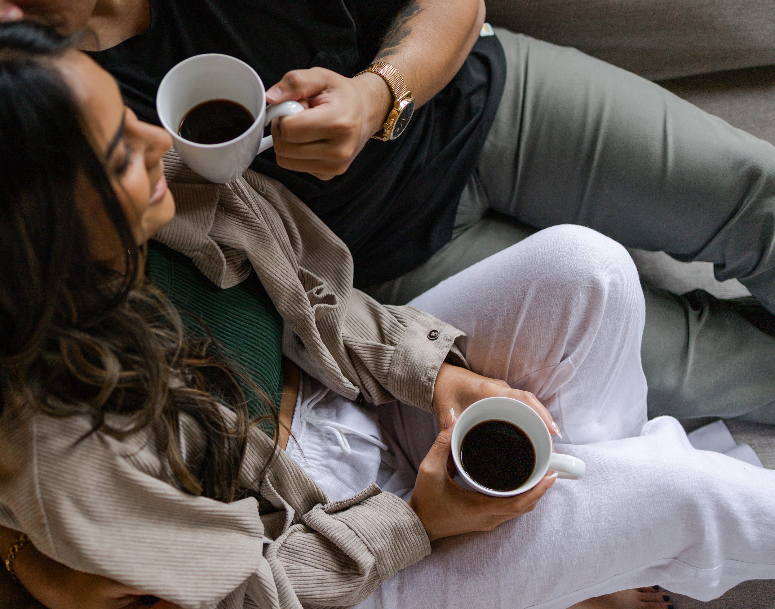 Aerial image of couple snuggling on the couch with morning coffee on their elopement day. Photography by Trail Magic Elopements and Micro Weddings.