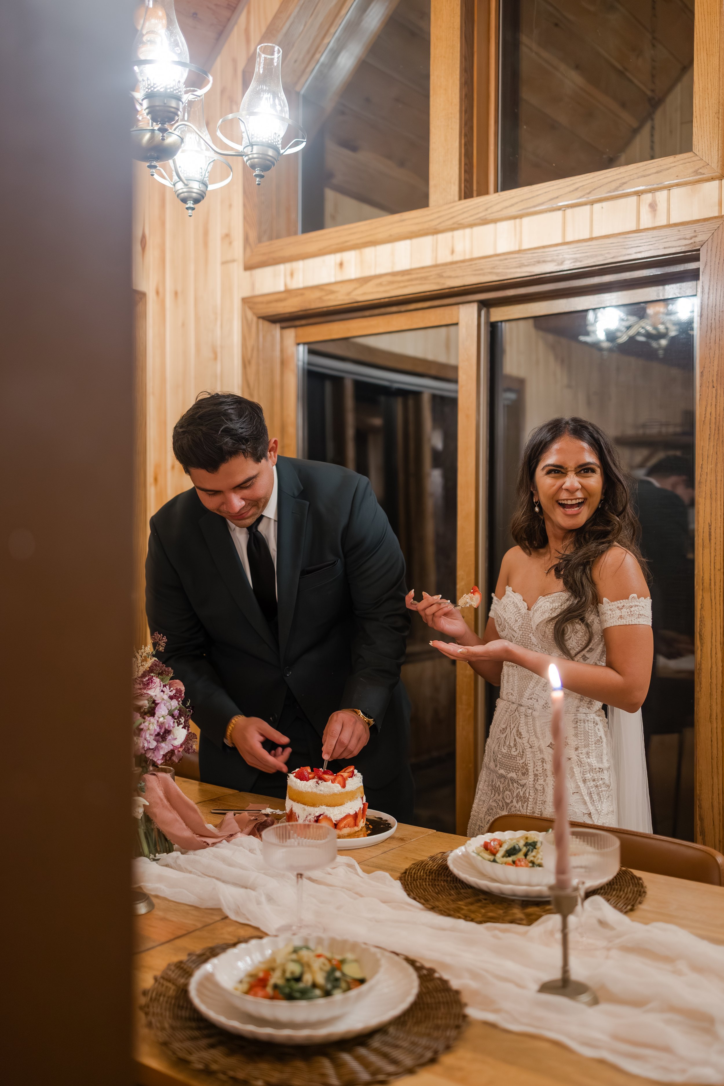 Couple cutting the cake on their elopement day in their cabin. Photography by Trail Magic Elopements and Micro Weddings.