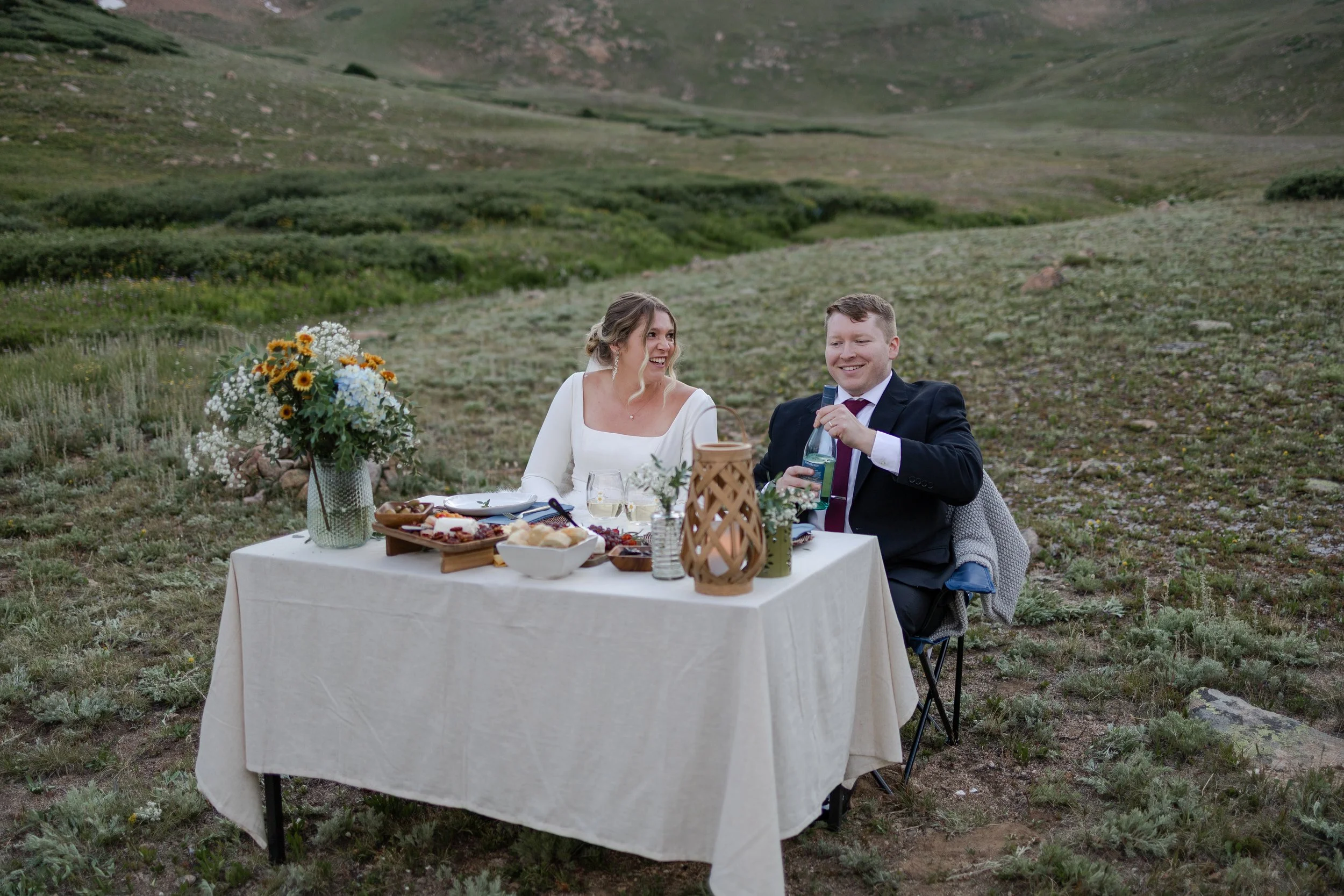 Couple celebrating their elopement with a beautiful charcuterie picnic set up by their Colorado Elopement Planner. Photography and Elopement Planning by Trail Magic Elopements and Micro Weddings.
