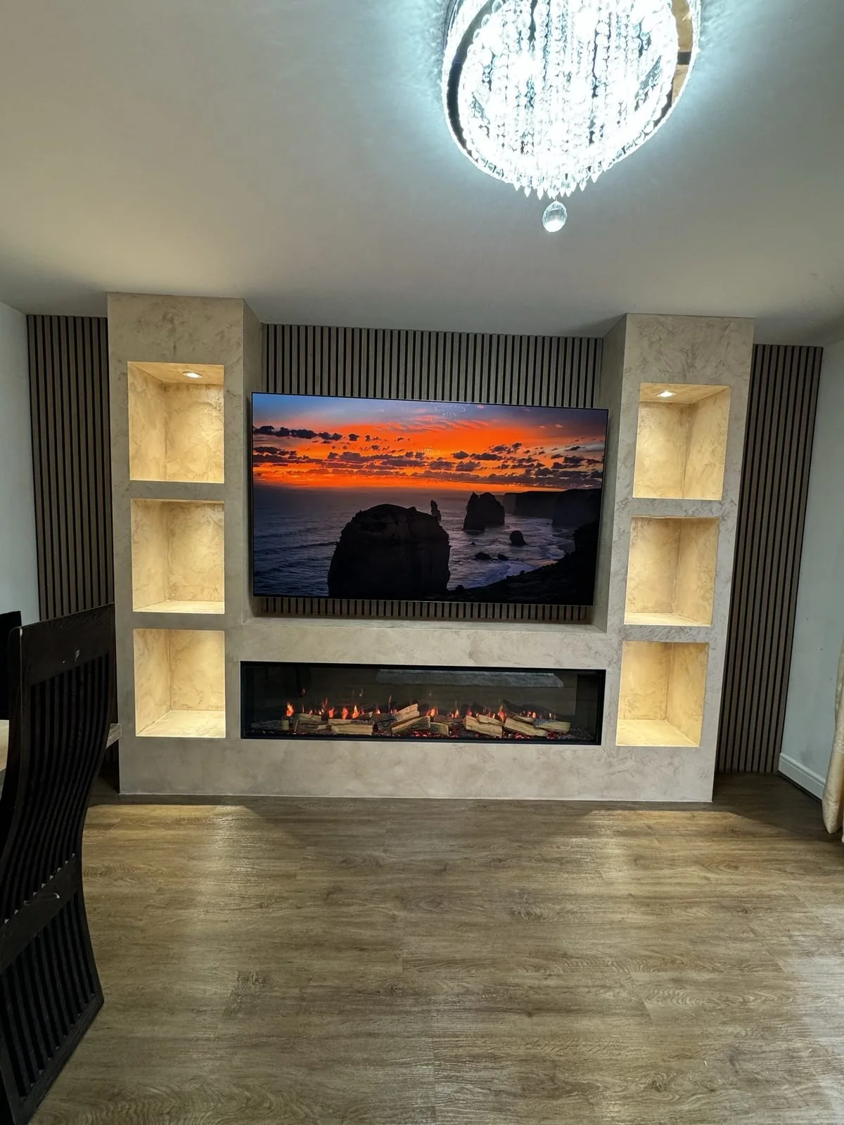 Finished stone-effect media wall with lit alcoves and slat panels in a Manchester home