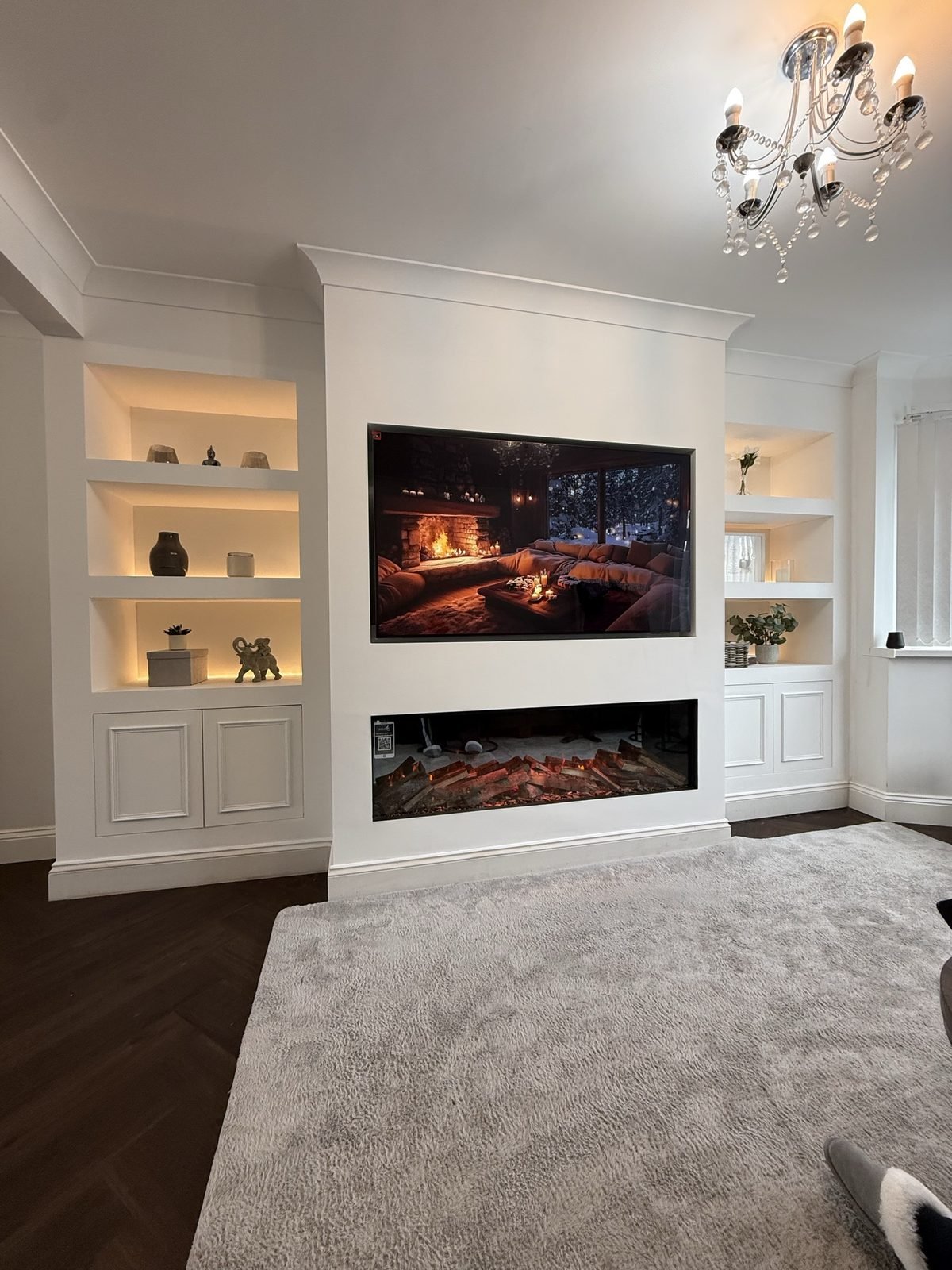 White media wall with lit shelving alcoves, cupboards and a built-in electric fire