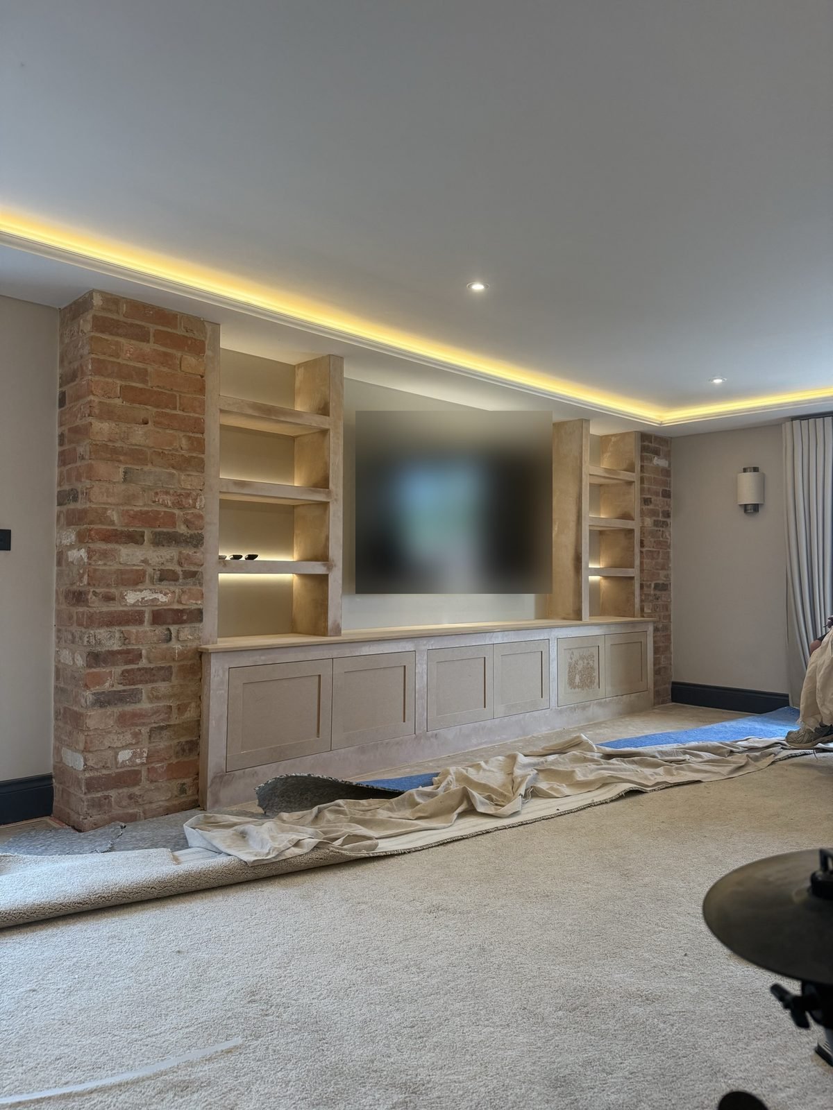 Media wall build stage, before plastering, with brick-effect pillars, shelving and LED lighting in the coving