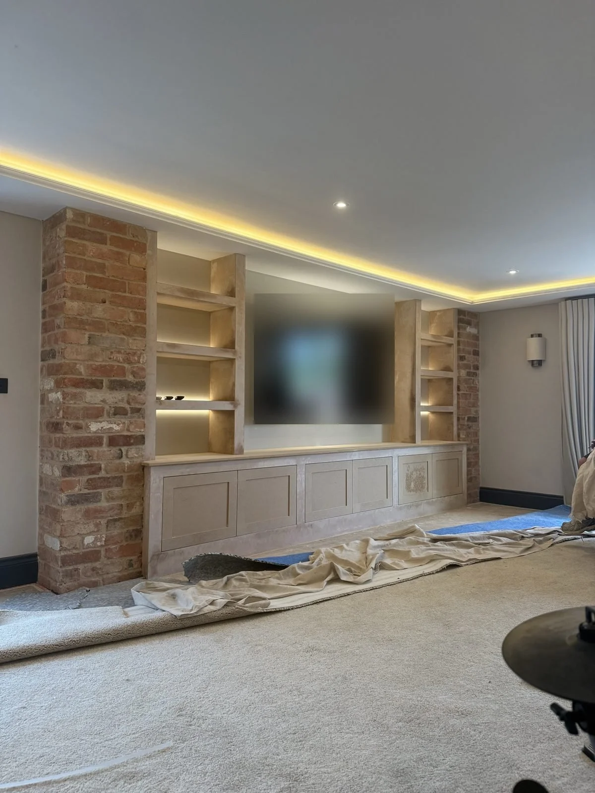 Media wall build stage, before plastering, with brick-effect pillars, shelving and LED lighting in the coving