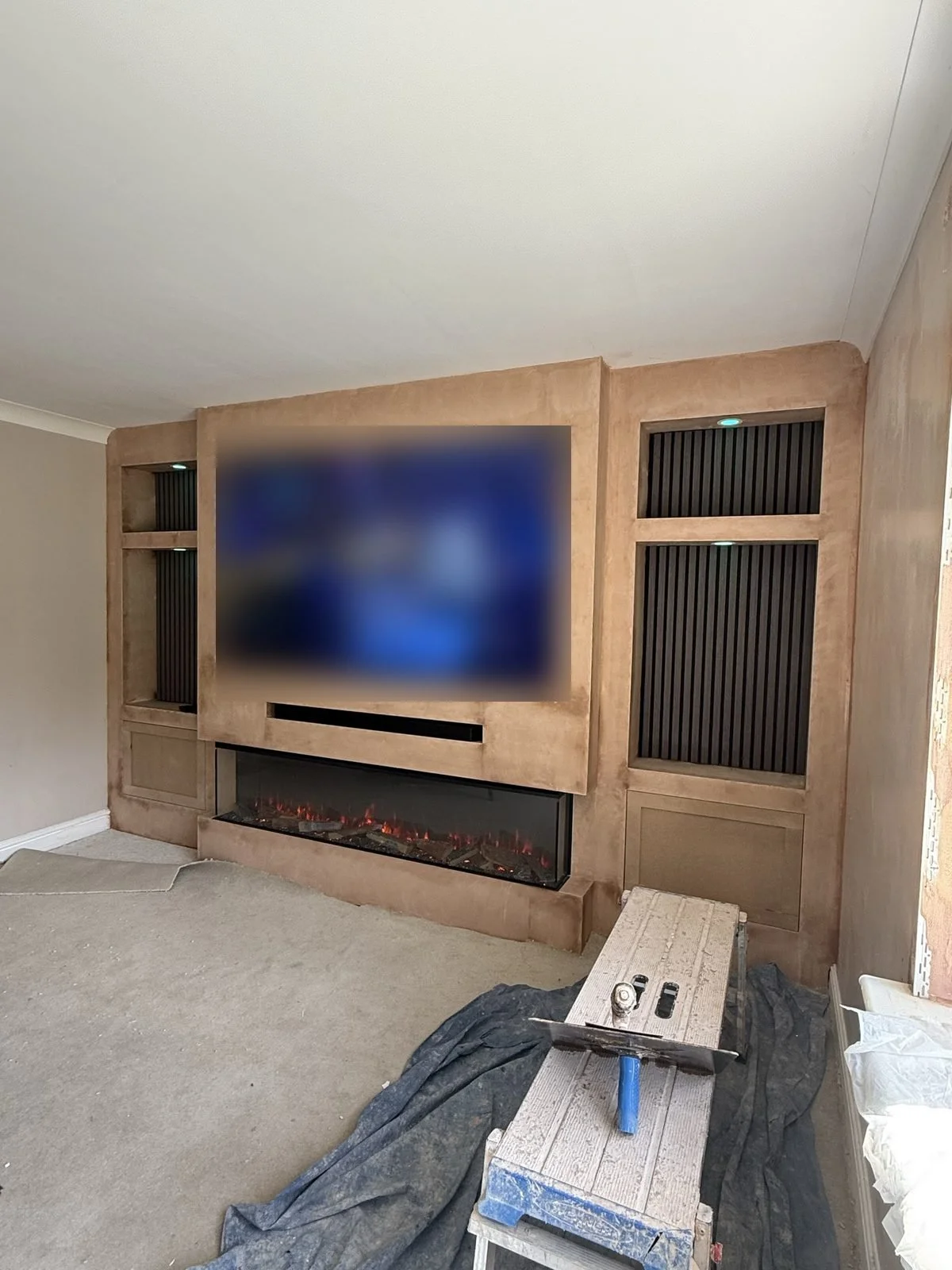 Media wall build in progress, before plastering, with TV, wide electric fire and slat panel alcoves