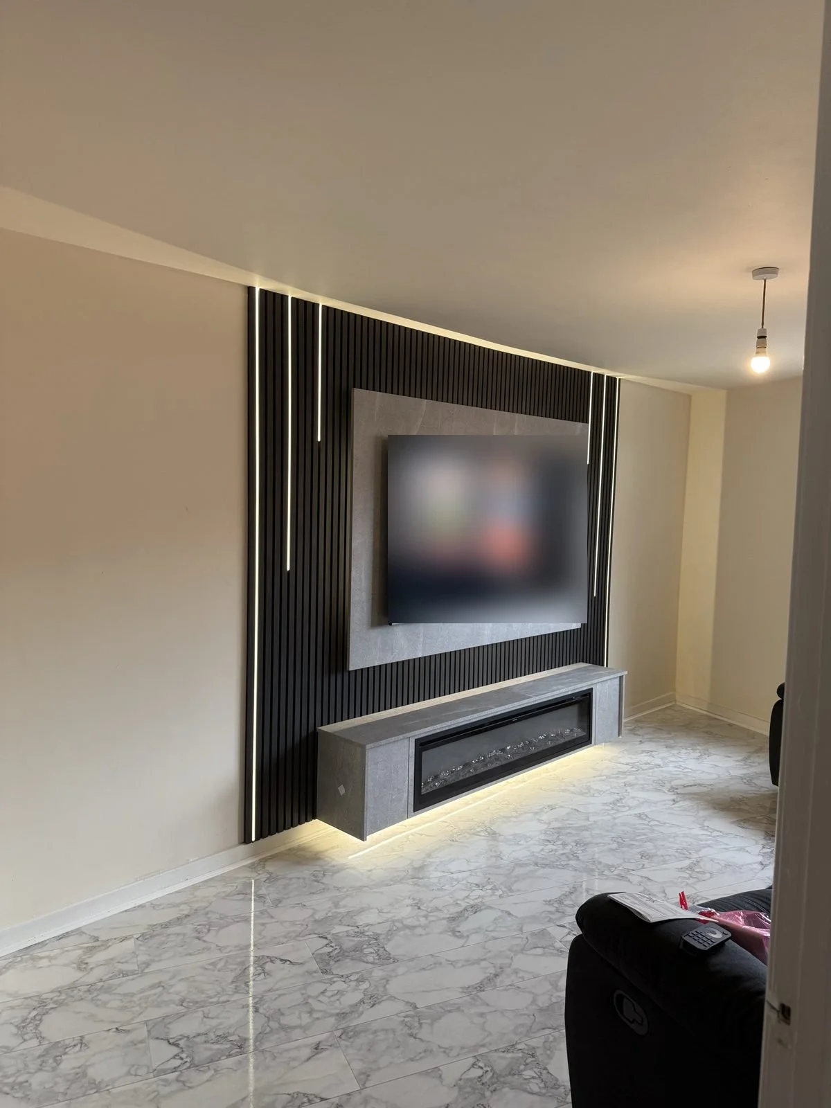 Black slat panel media wall with vertical LED strips and a floating unit with electric fire
