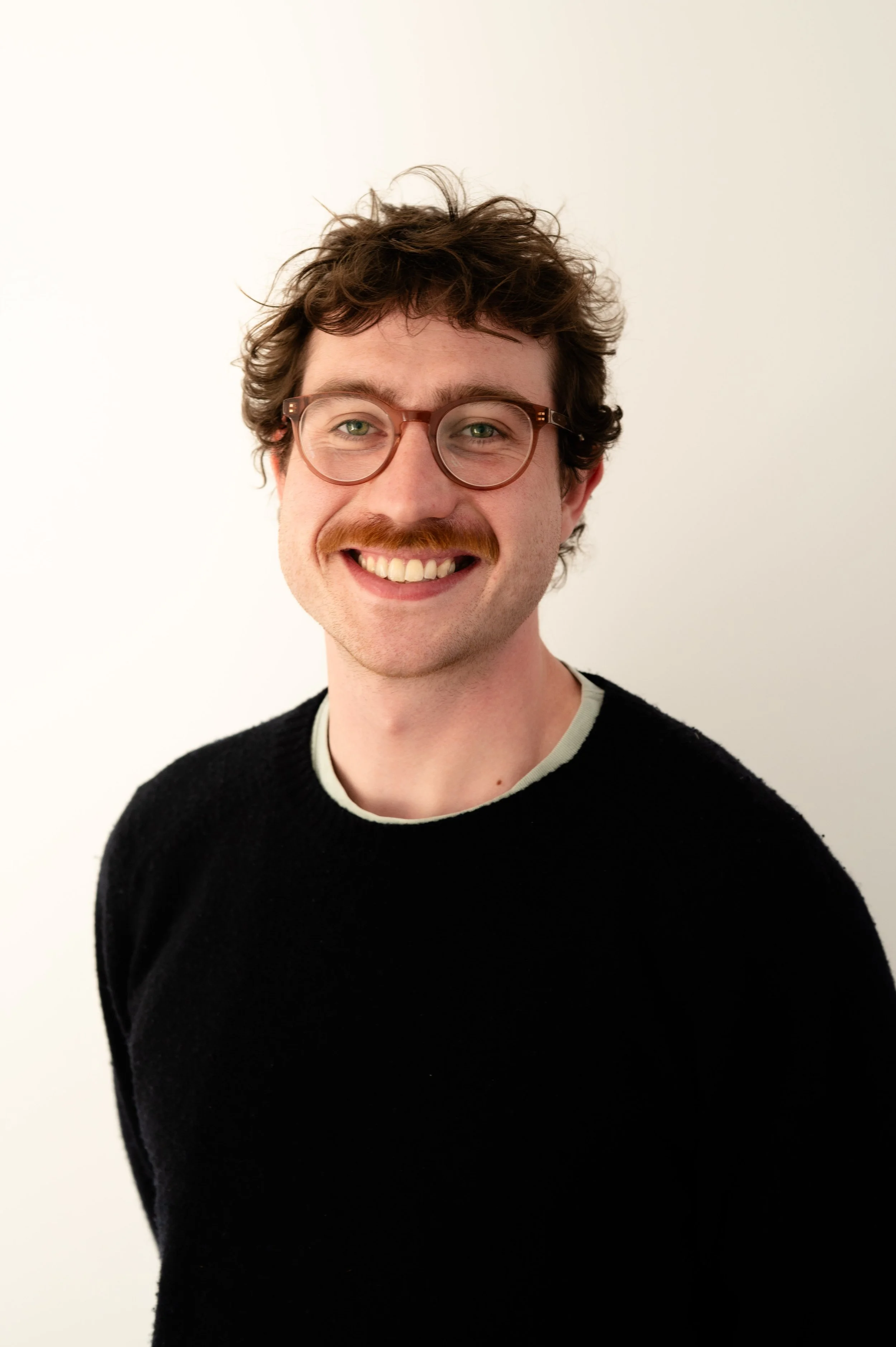 Profile of Ted Turver - a training psychotherapist at The Brixton Practice in London, wearing a black jumper and glasses.