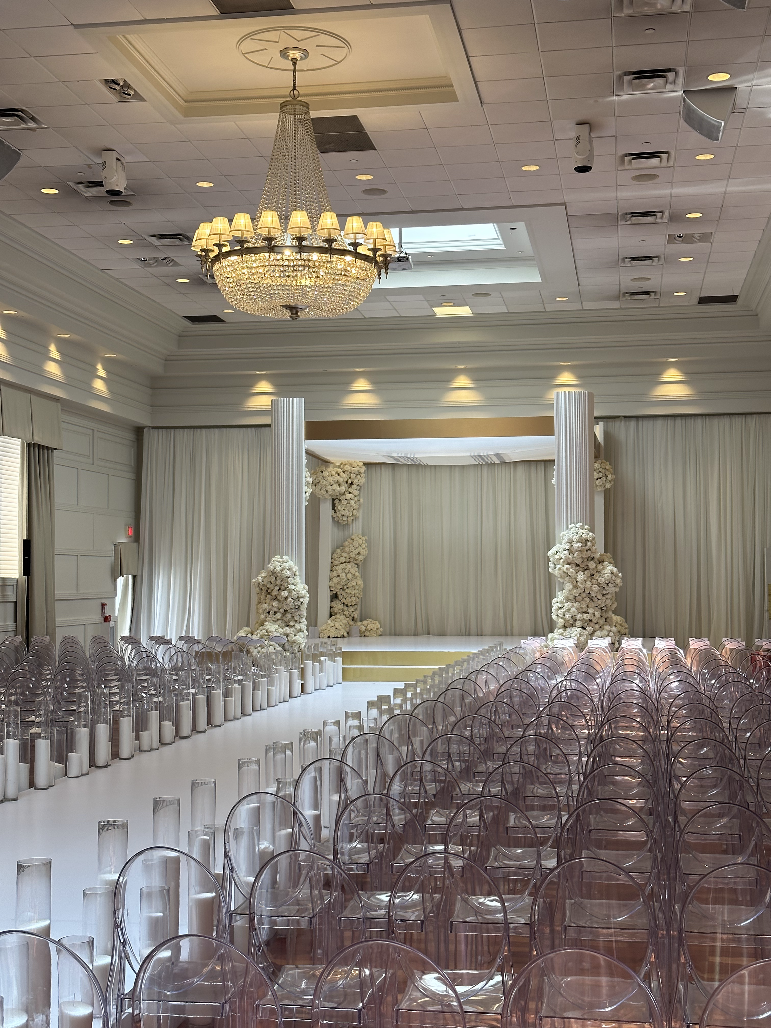 Modern Wedding Ceremony with Ghost Chairs and White Floral Chuppah