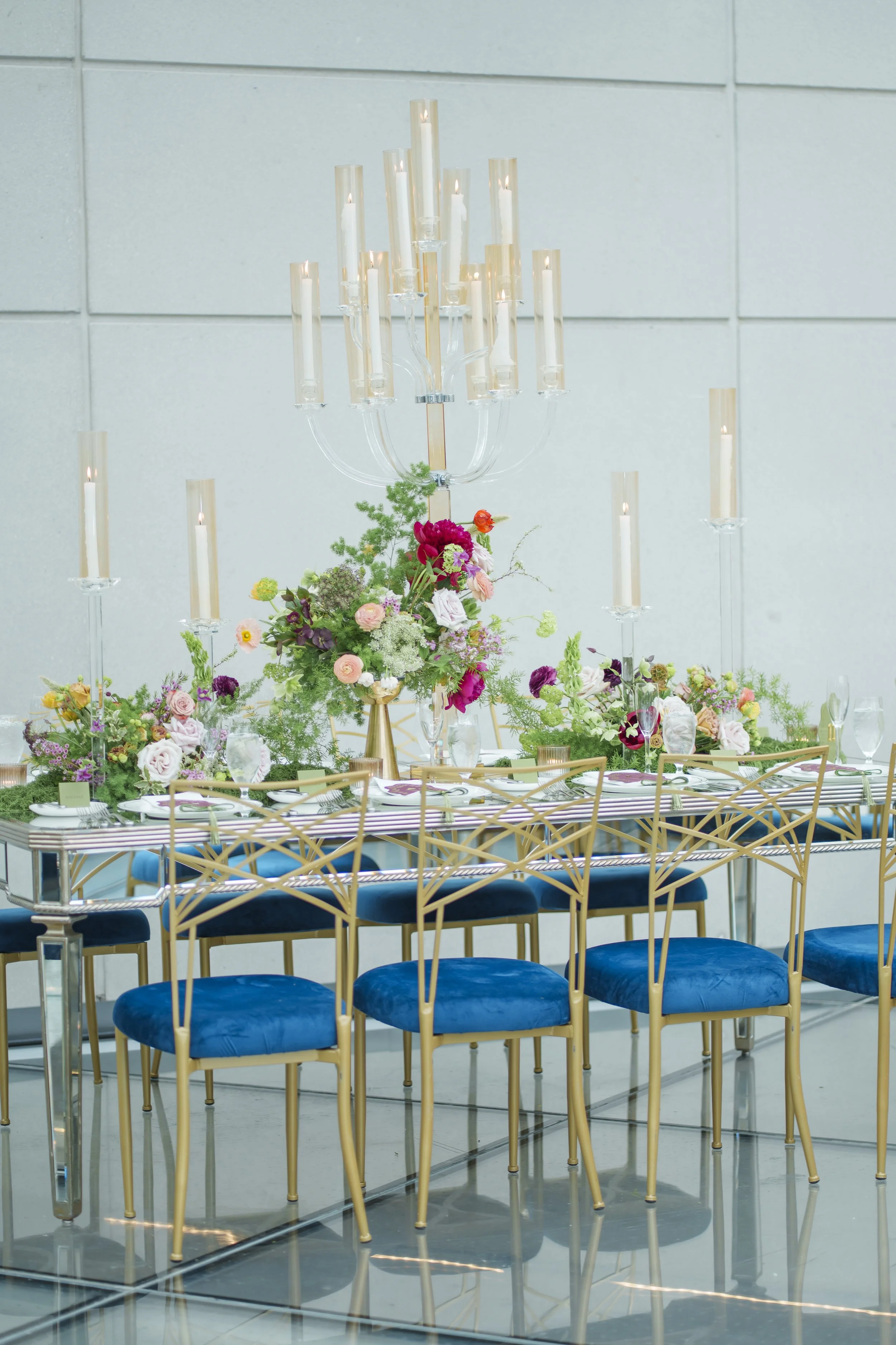 Hotel X Toronto reception table with gold candelabras, jewel-toned florals and blue velvet chairs
