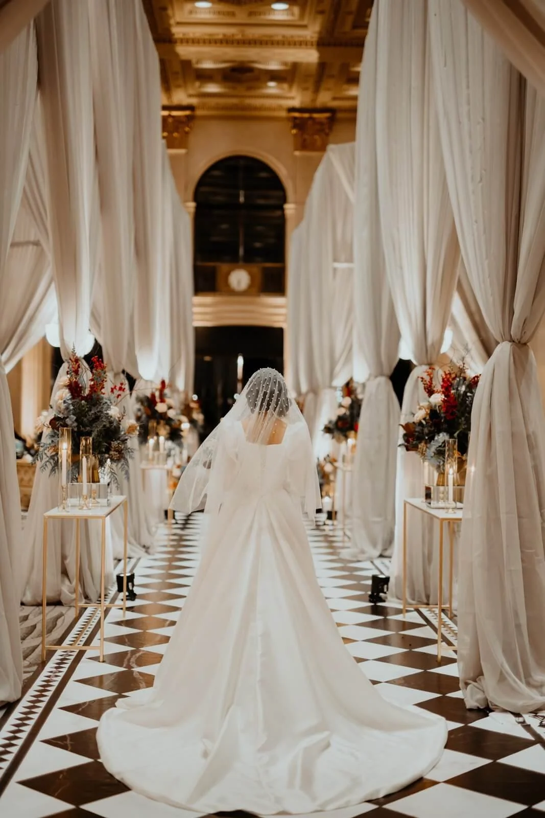 Bride walking down a beautifully draped aisle with elegant floral arrangements. Perfect for luxury wedding decor and custom event design in Toronto.