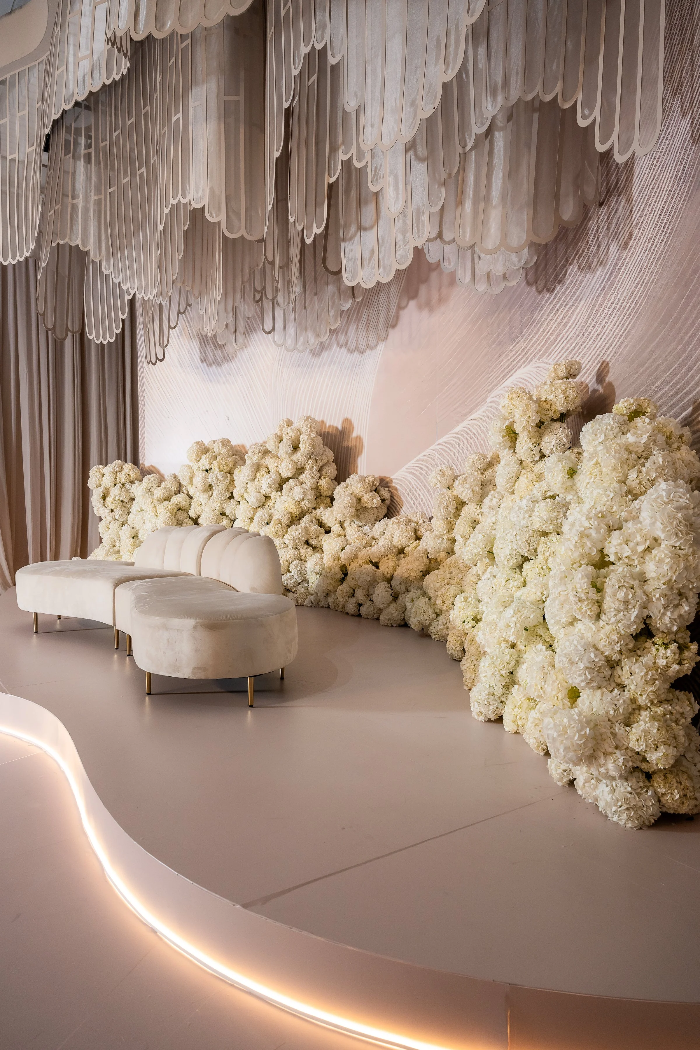 The Kabbalat Panim room: a laser-cut swirl ceiling installation over a bed of white hydrangea and an ivory velvet love seat. Design, florals & décor by Ethereal Creators.