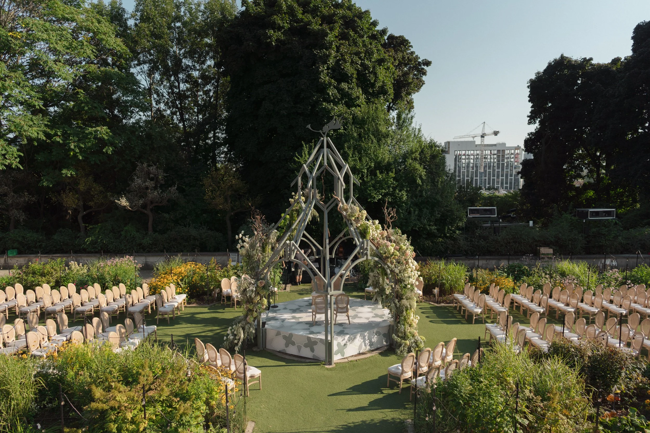 Outdoor wedding ceremony at the Casa Loma Gazebo, Toronto, showcasing a symmetrical garden layout with custom seating and floral ceremony decor.