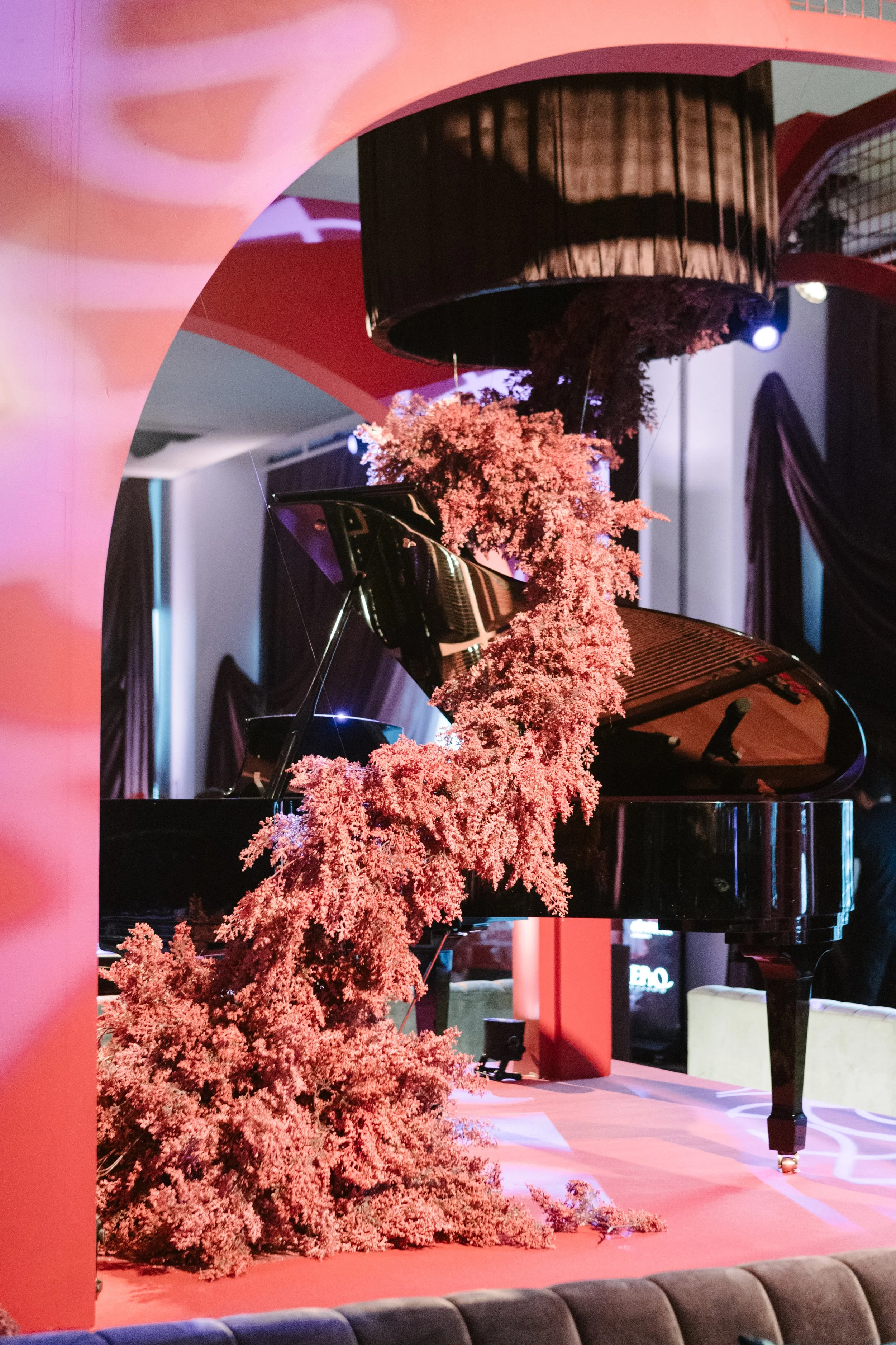 A black grand piano decorated with pink flowers in an elegant interior setting.