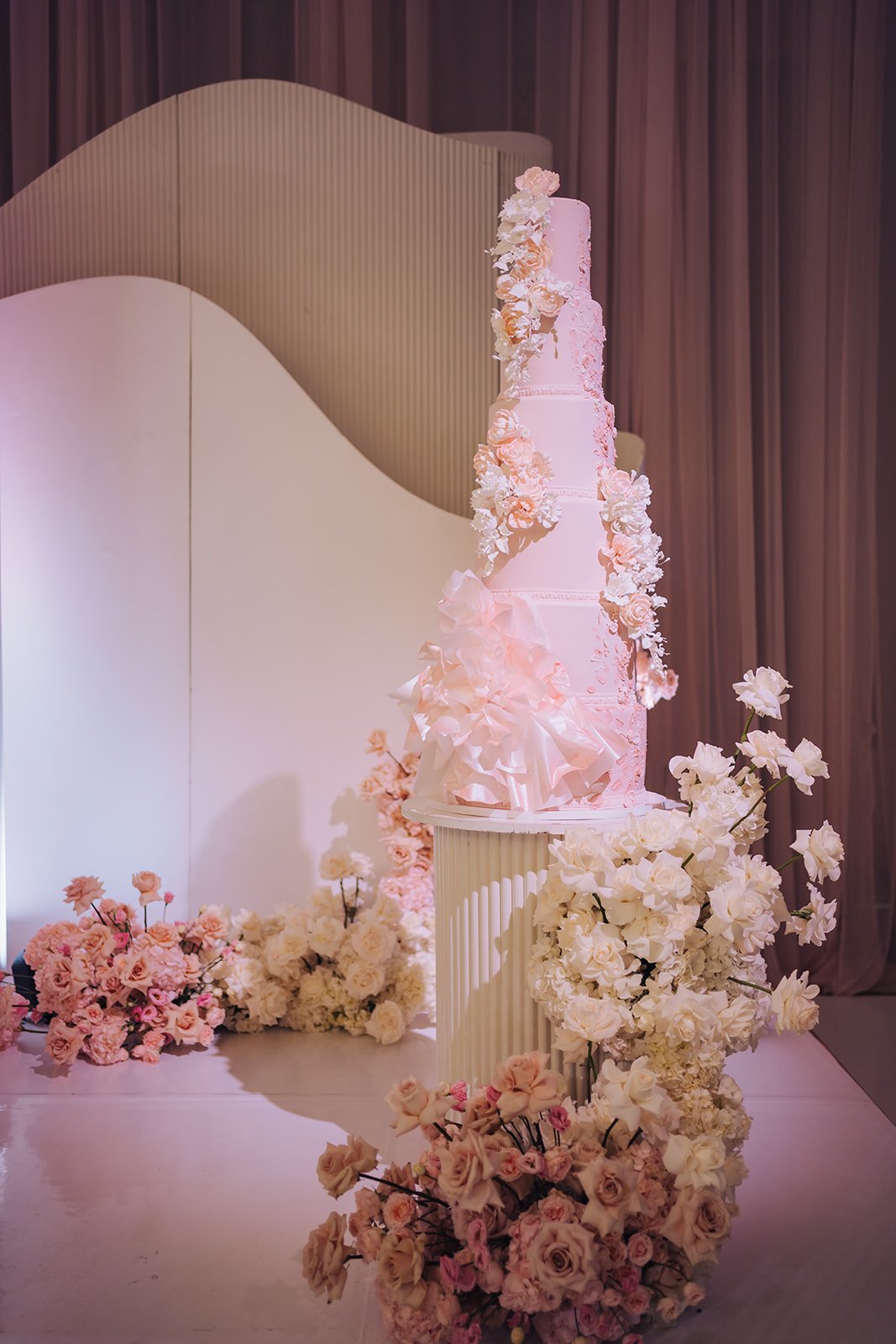 Tall blush multi-tier wedding cake with cascading pink and ivory sugar florals at Château Le Parc, by Ethereal Creators.