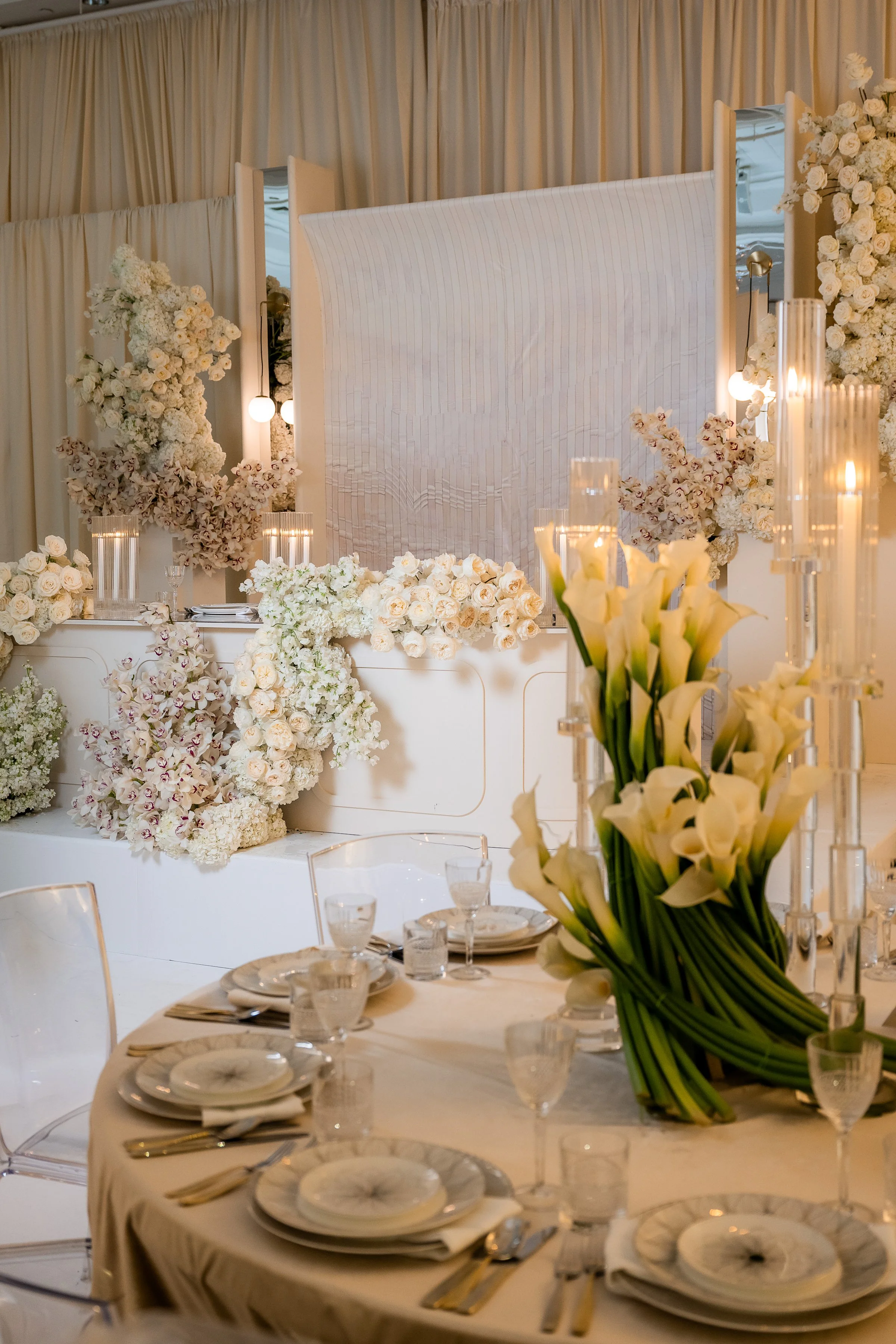 All-white wedding sweetheart table with cascading white florals, mirrored panels and calla lily centrepieces by Ethereal Creators.