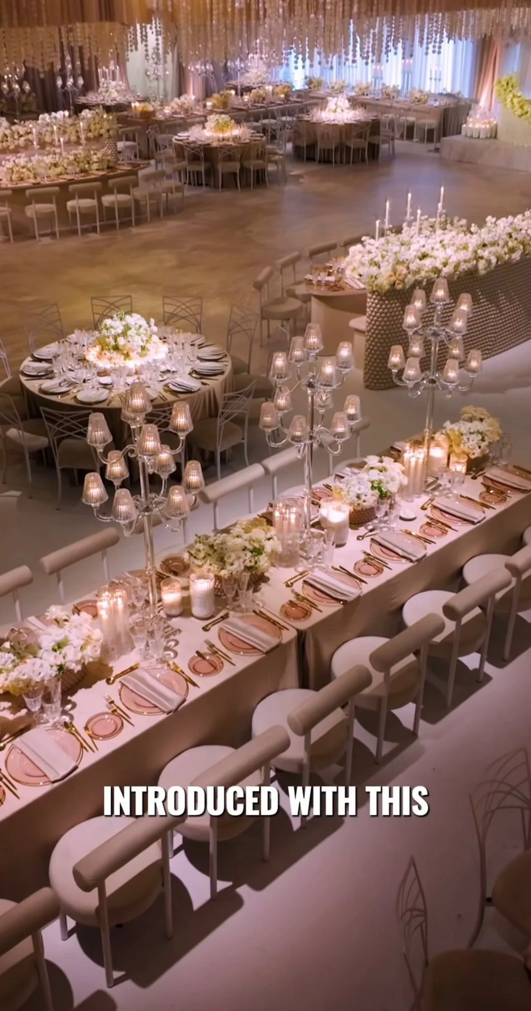 Elegant banquet hall decorated with floral arrangements, candles, and chandeliers for a special event.