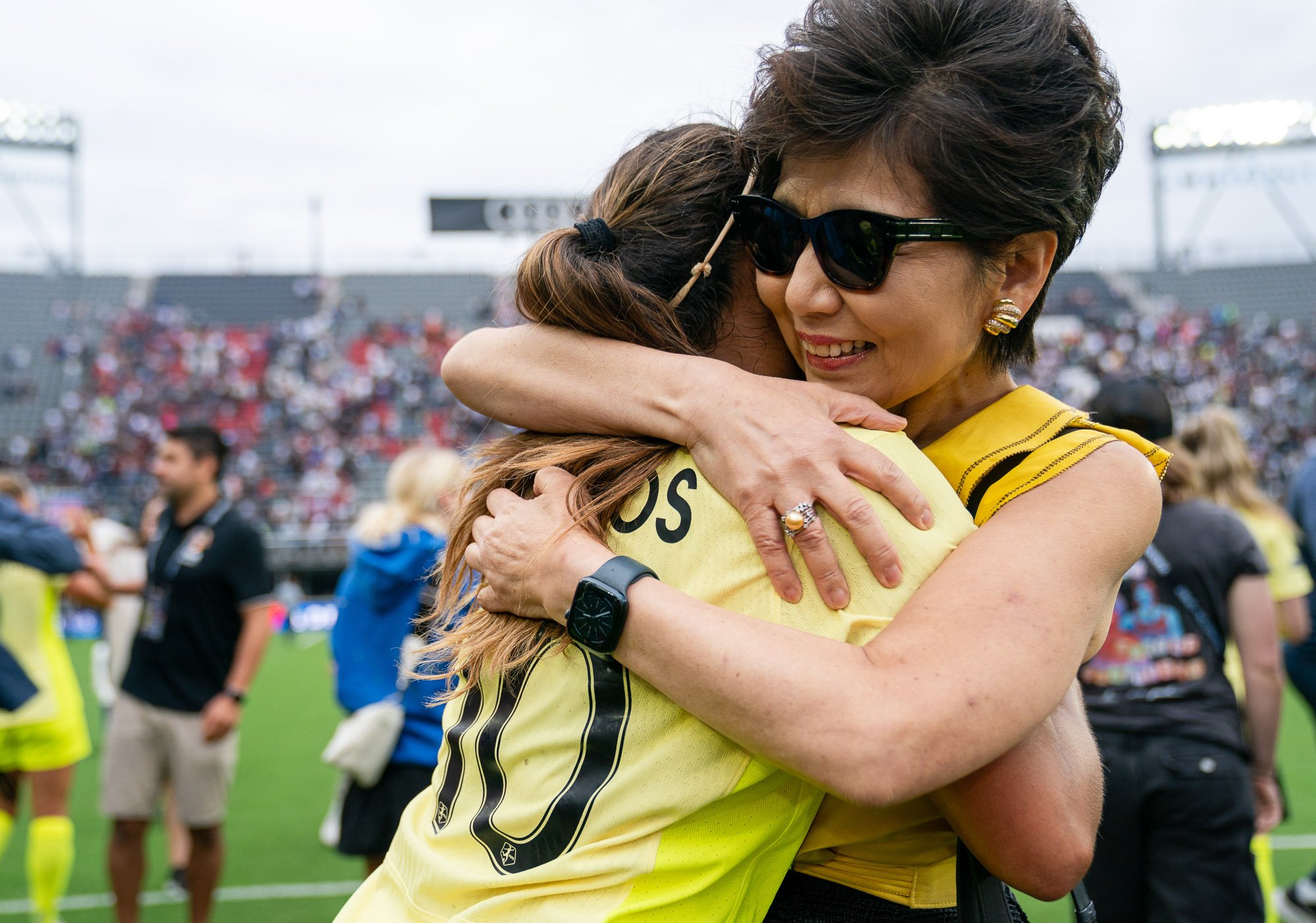 Washington Spirit owner Michele Kang embraces midfielder Leicy Santos following a victory over the Portland Thorns at Audi Field in 2024, smiling during the postgame moment on the field. (Cody Cervenka/Crvnka Photography)