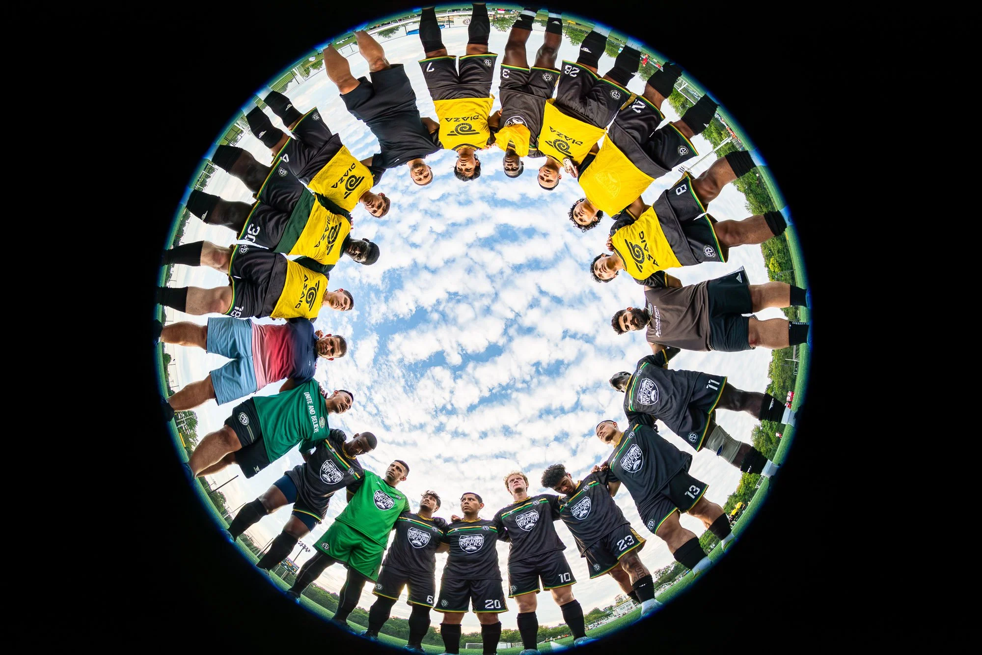 Frederick Skyline CF players and staff gather in a pregame huddle before their UPSL match against Germantown City FC at Ballenger Creek Park on August 12, 2023. The image was captured using a fisheye lens placed at ground level with a remote trigger,