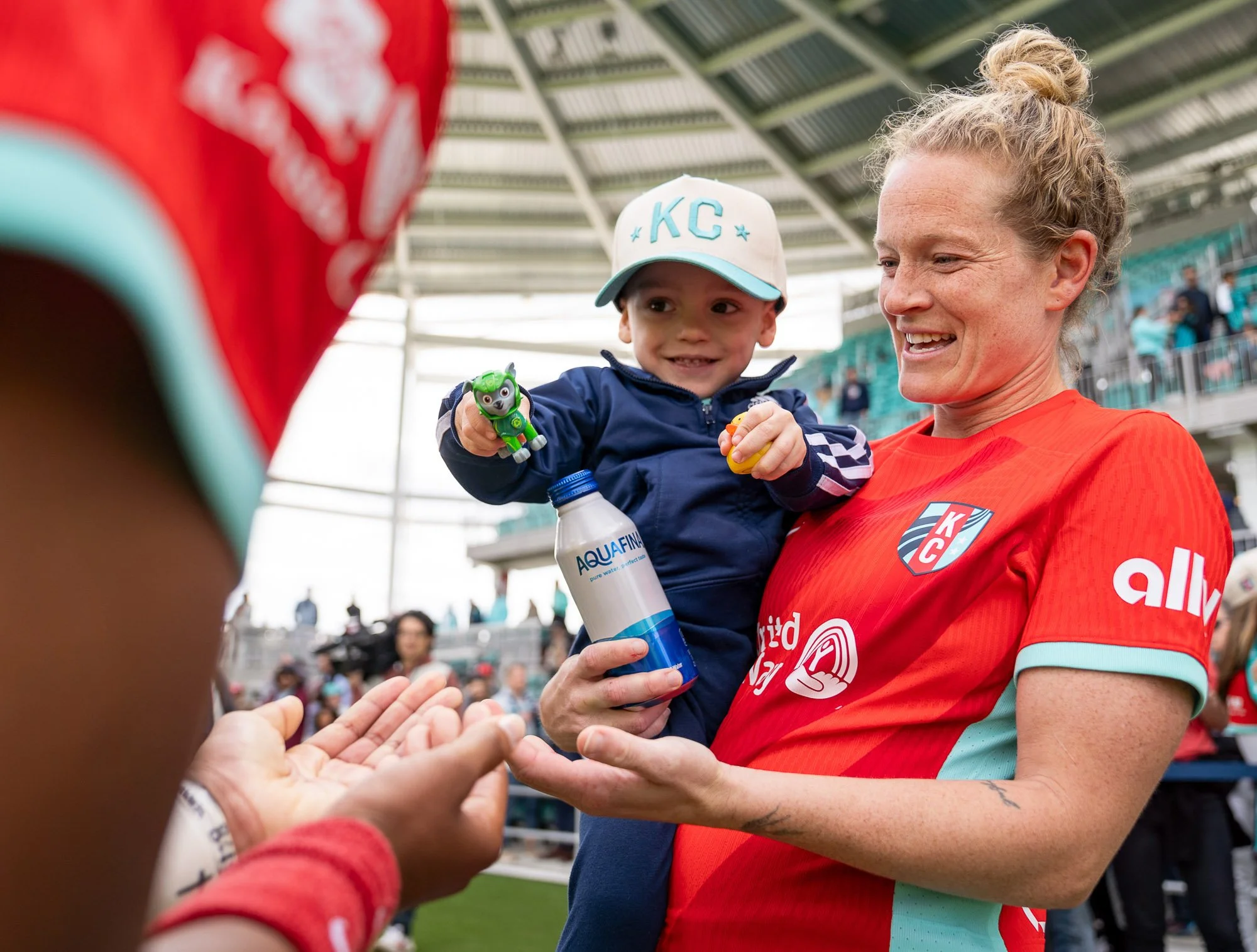 Kansas City Current forward Kristen Hamilton holds a young fan while interacting with another player following the inaugural match at CPKC Stadium on March 16, 2024, a 5-4 victory over the Portland Thorns. (Cody Cervenka/Crvnka Photography)