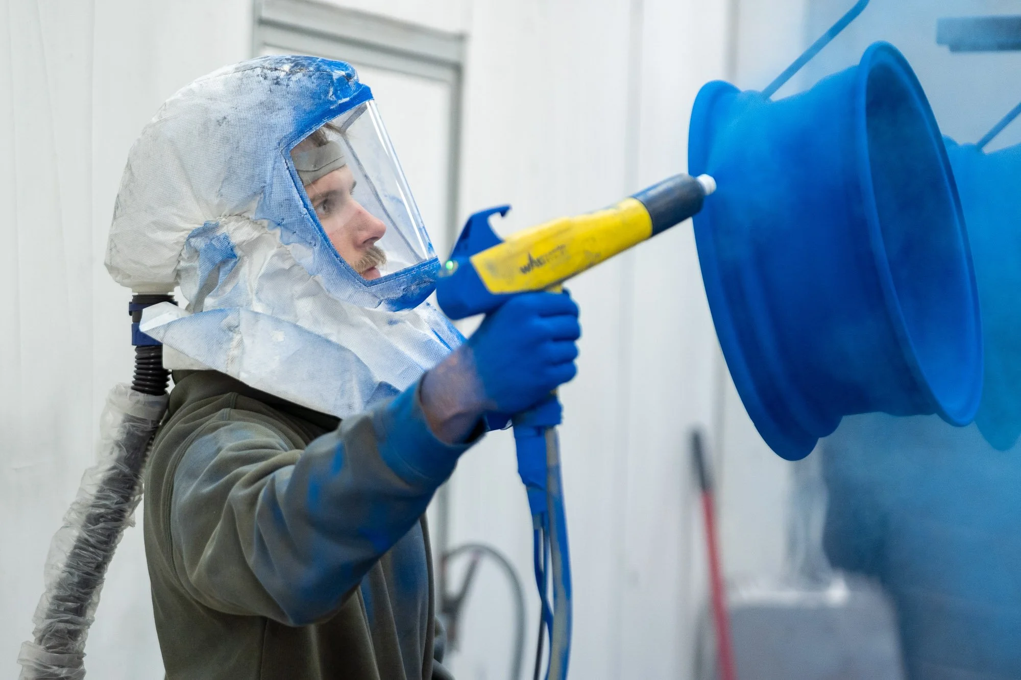 biltwood-powder-coating-employee-spraying-blue-powder-wheel-waynesboro-pa-commercial-branding-photography.JPG