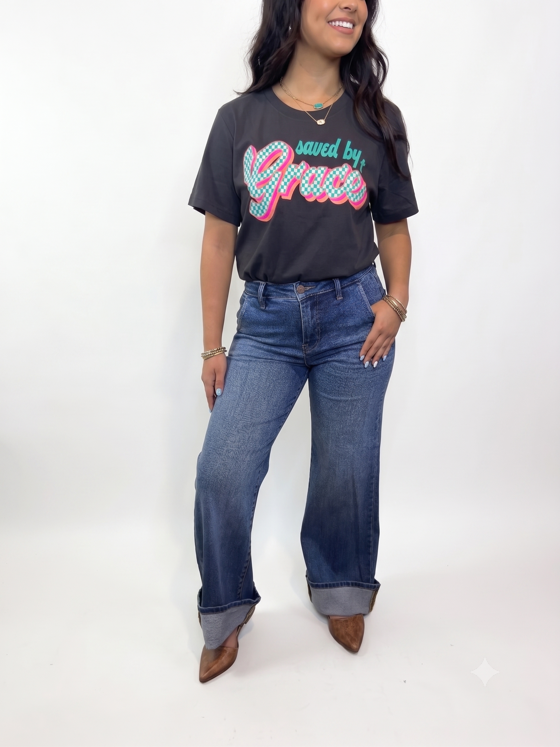 Person wearing a striped short-sleeve sweater with high-waisted blue jeans, standing indoors with a cowhide-patterned backdrop.