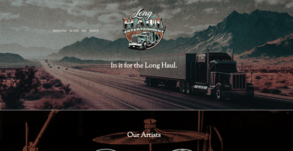 A black semi-truck driving on a long, open highway through a desert landscape with mountains in the background. The image features a logo for Song Haul Entertainment with a retro truck and the tagline 'In it for the Long Haul.'