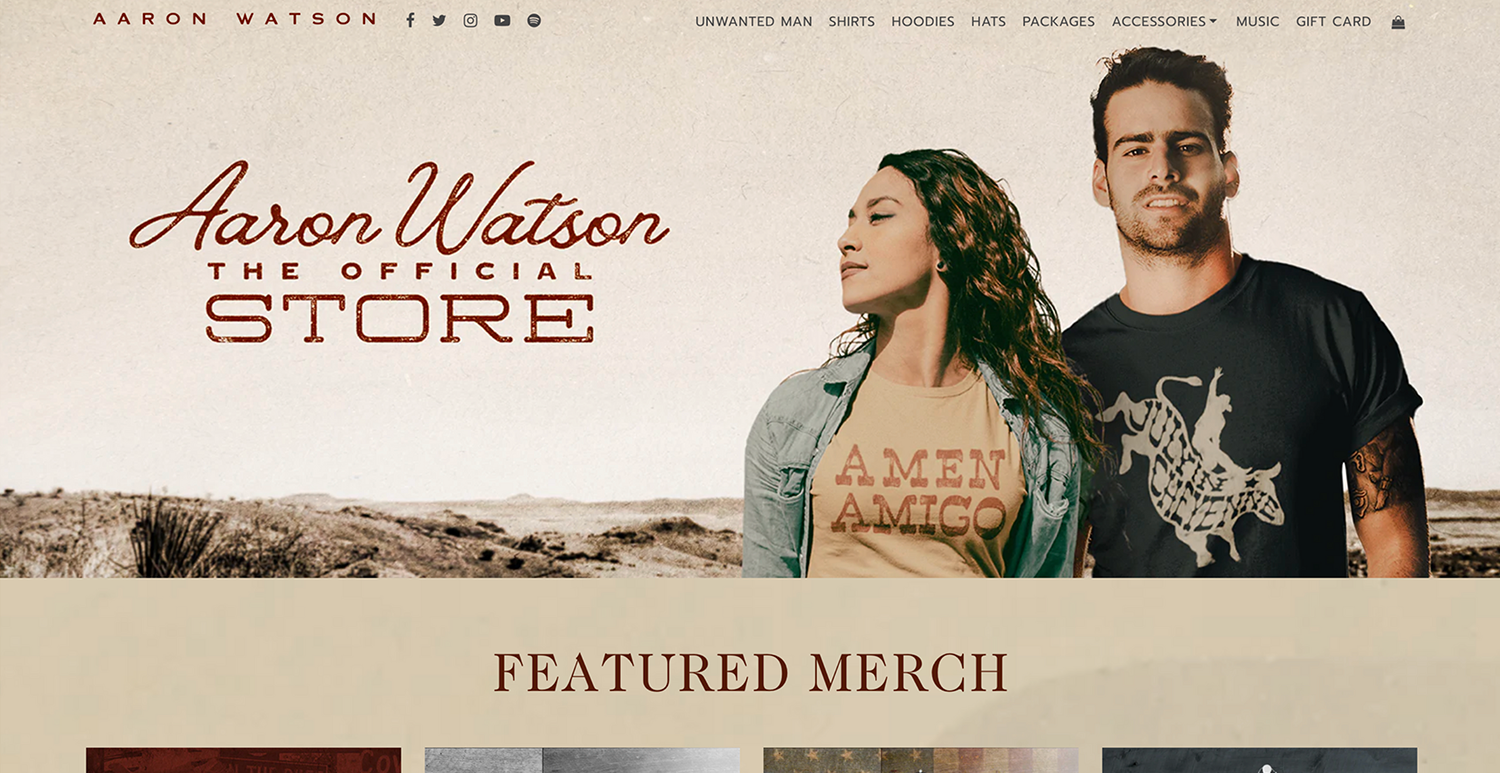 Website homepage for Aaron Watson's official store featuring a man and a woman standing outdoors, with the store name and navigation menu at the top.