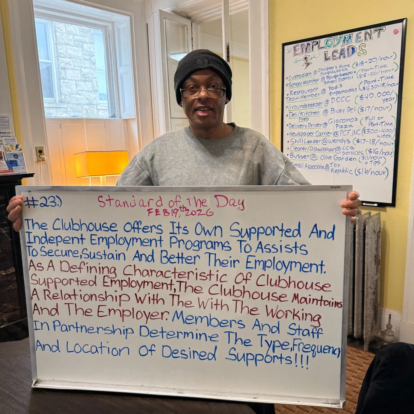 Employment is one of the many recovery goals every accredited Clubhouse helps members pursue if they wish. Curtis copies standard 23 onto the white board, which states the importance of employment support offered by all clubhouses. Behind him is a di