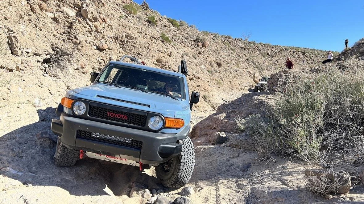 Blue Toyota FJ Cruiser with a red Toyota logo rock crawling