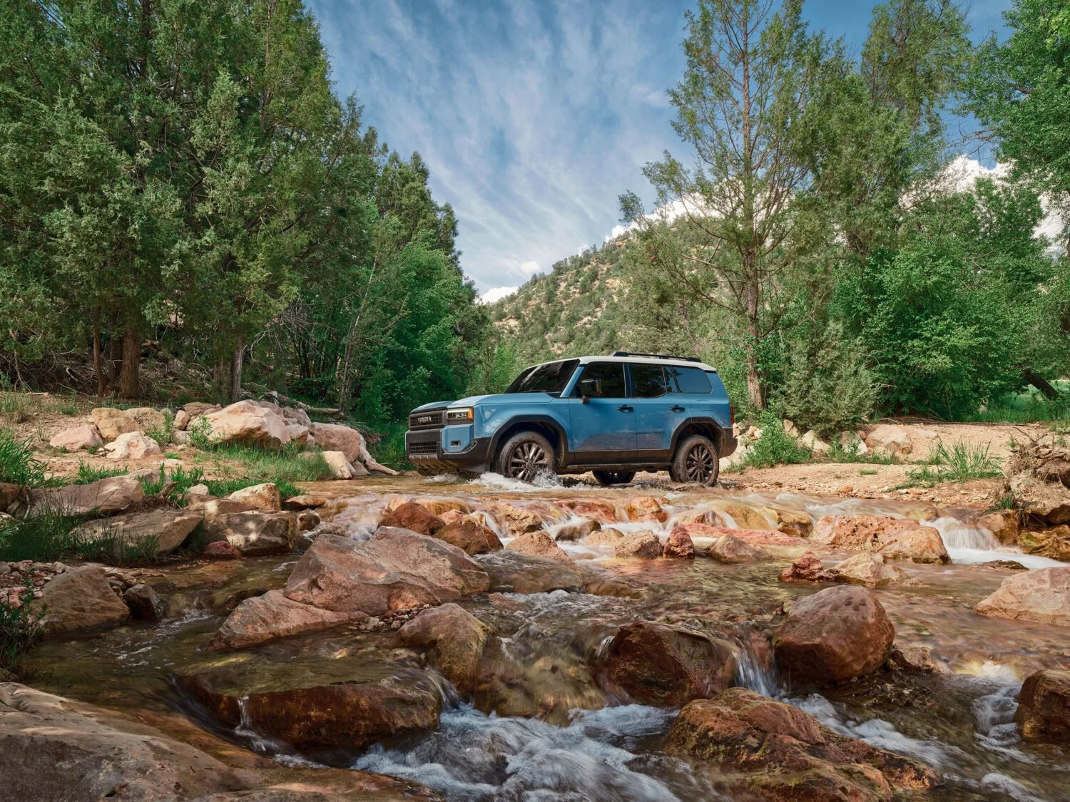 Toyota Land Cruiser crossing a river while driving over rocks