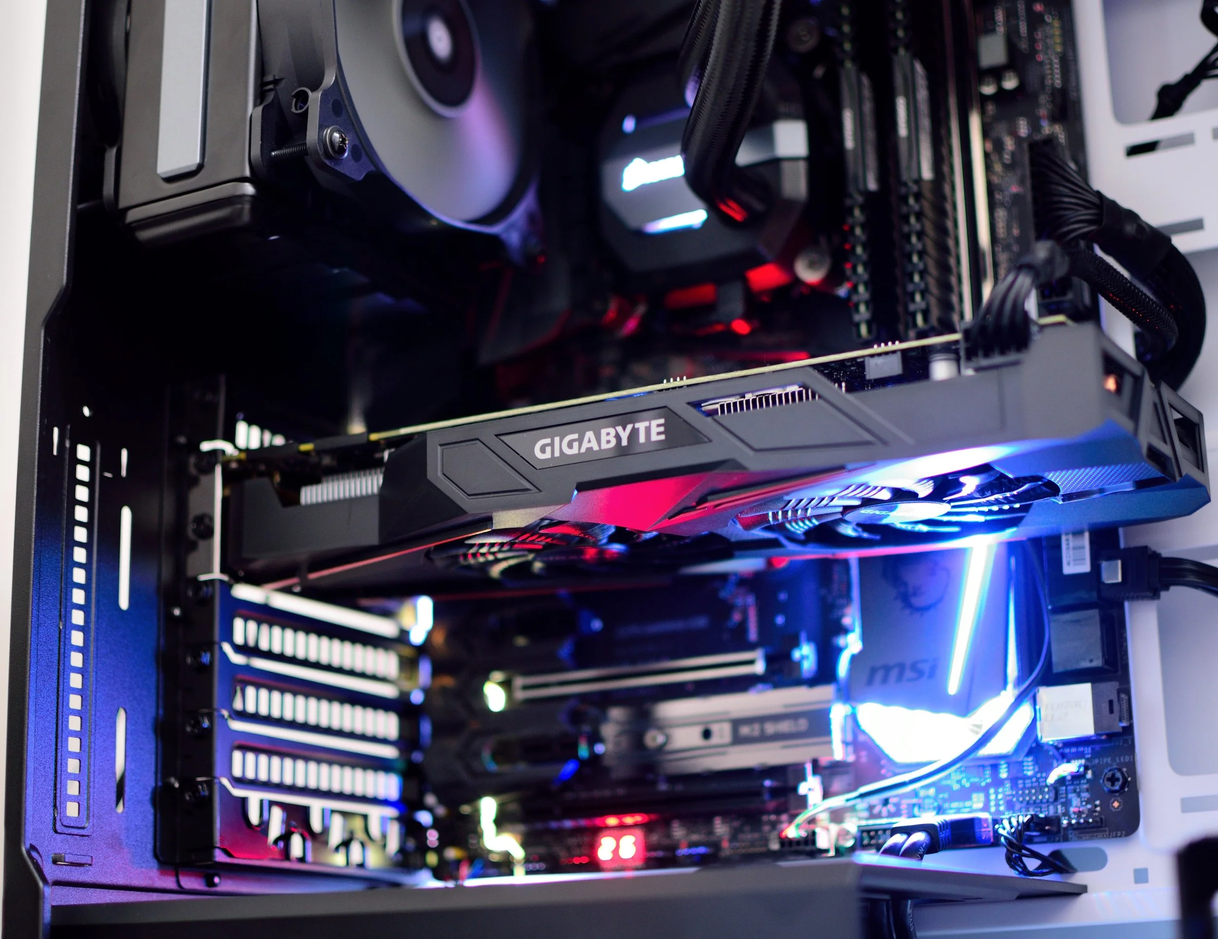 Interior view of a gaming or high-performance computer showing a Gigabyte graphics card, an MSI motherboard, RAM sticks, cooling fans, and LED lighting.