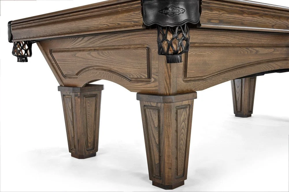 Close-up of a wooden billiards or pool table corner with a black leather pocket and detailed woodwork.